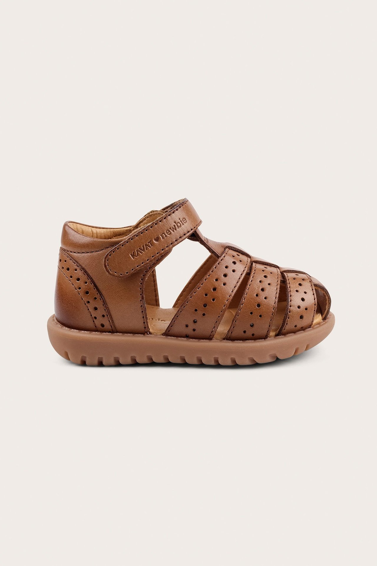 Side view of a brown leather baby sandal with perforated straps and hook-and-loop fastening.