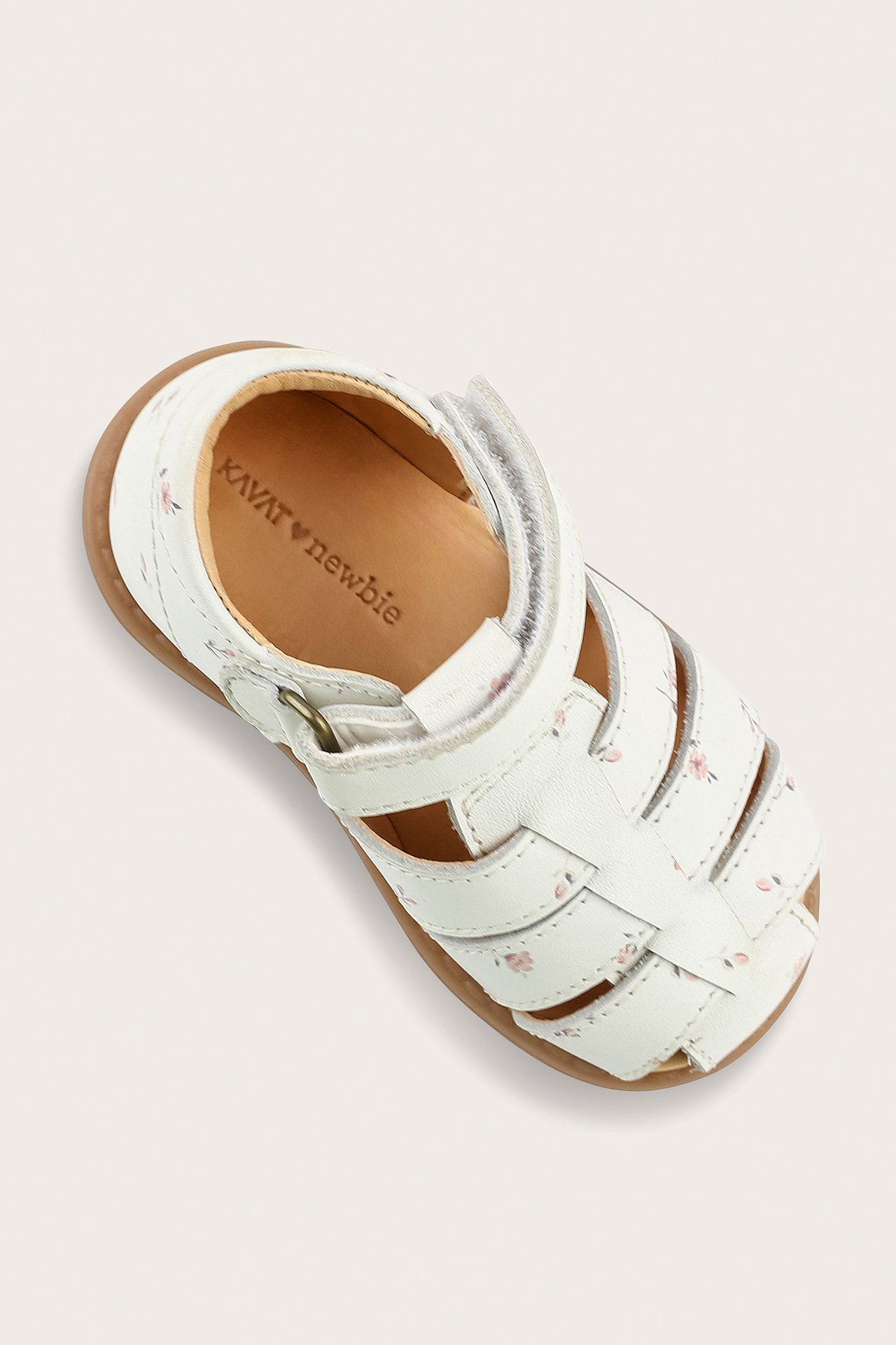Close-up of a white baby leather sandal with a pink floral pattern and hook-and-loop fastening.
