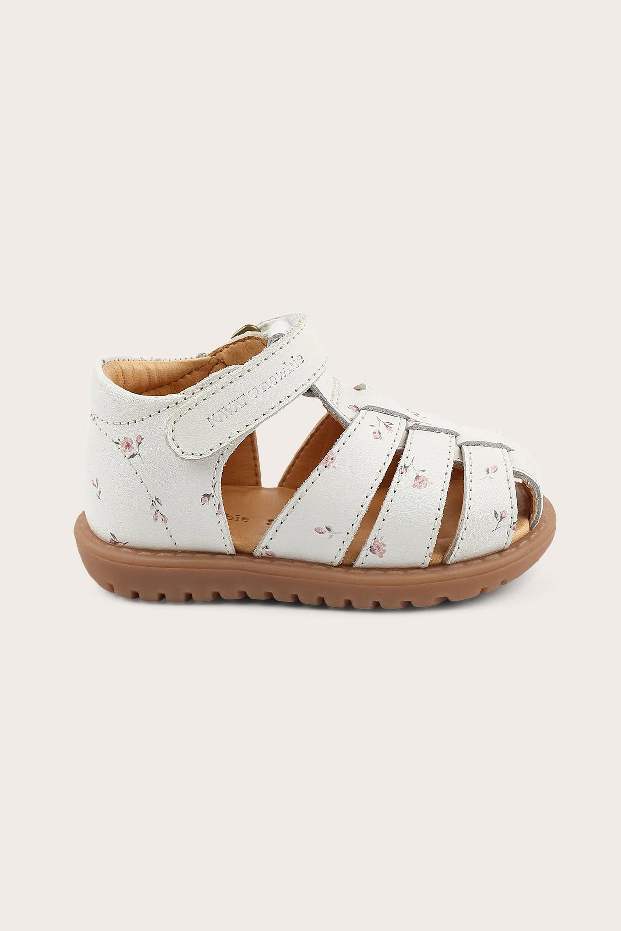 Side view of a white leather kid's sandal with a light pink floral pattern and a hook-and-loop strap.