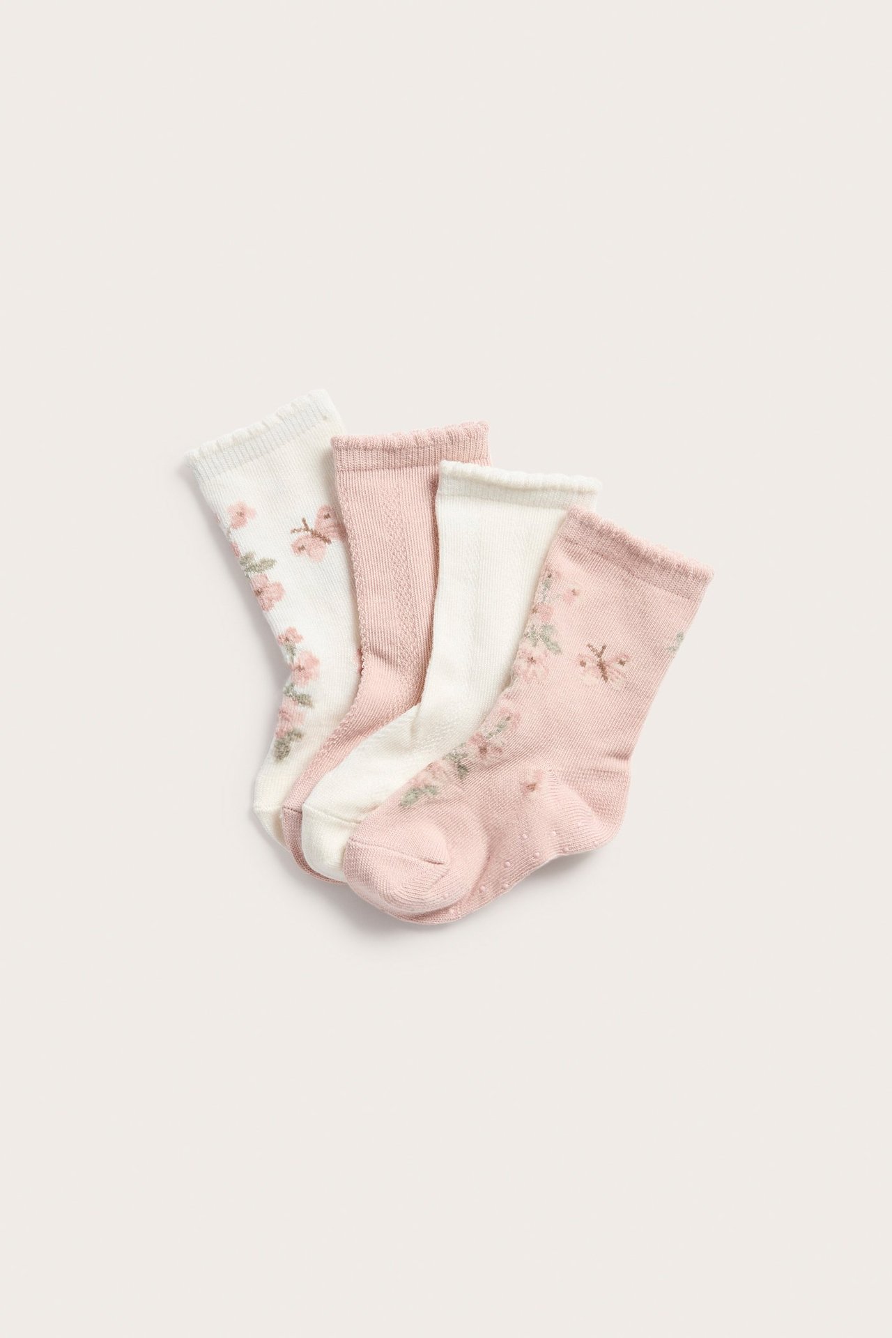 Draufsicht auf vier Babysocken: zwei mit Blumenmuster (gebrochenes Weiß, rosa) und zwei strukturiert (rosa, gebrochenes Weiß).