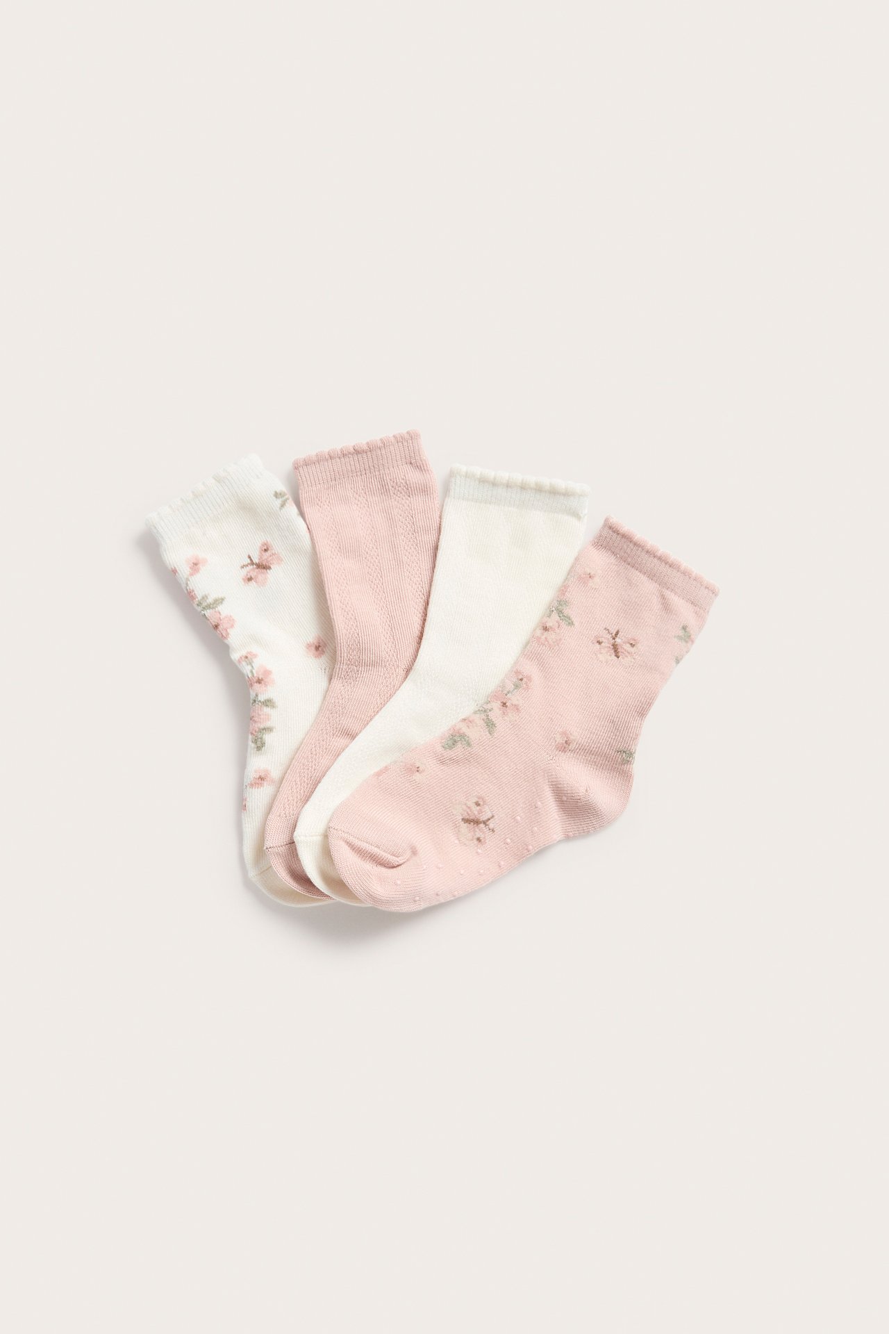 Draufsicht auf vier Babysocken: cremeweiß geblümt, einfarbig rosa, einfarbig cremeweiß, rosa geblümt mit Antirutsch.