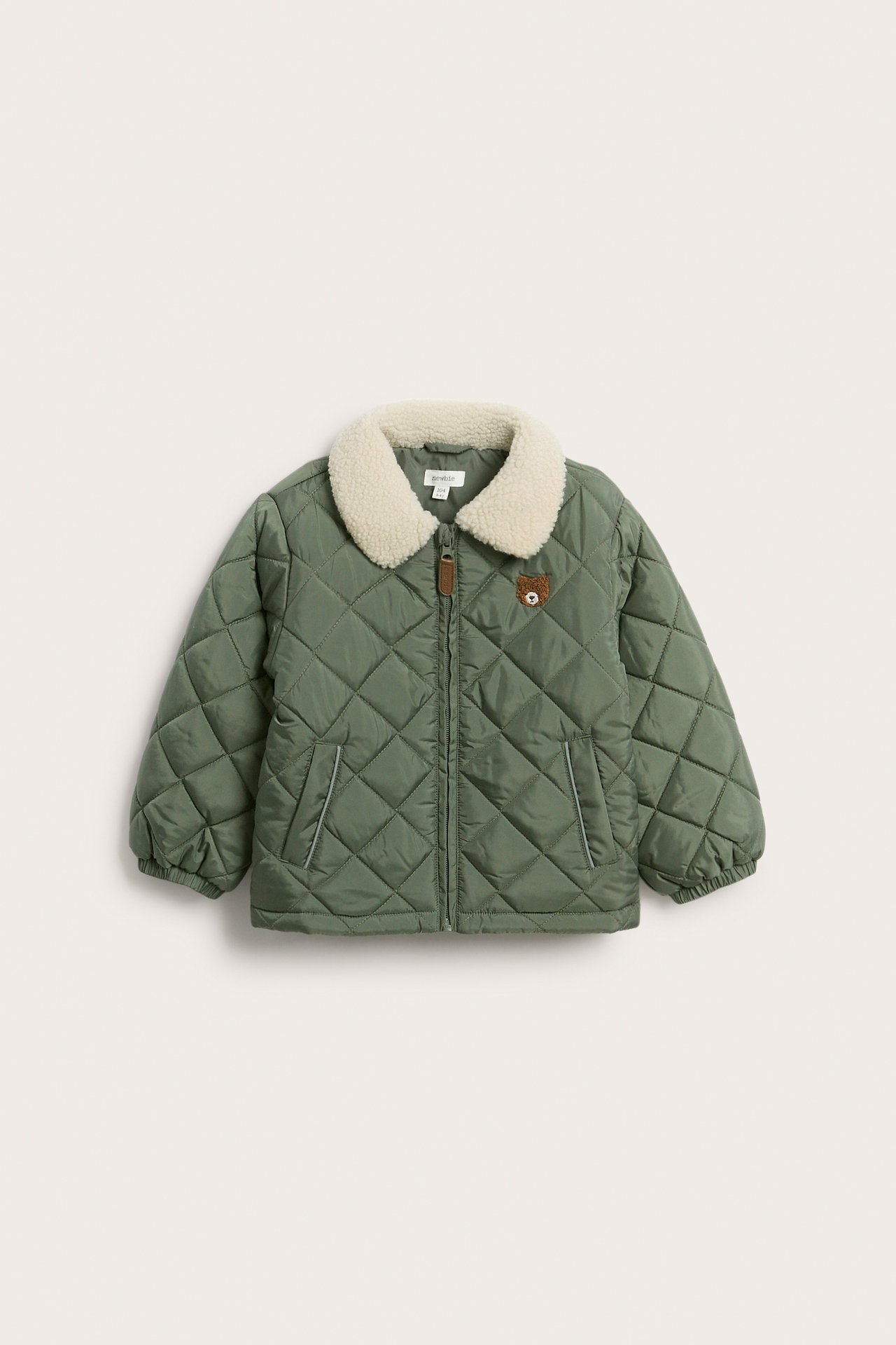 Front view of a kid's dark green quilted jacket with a cream pile collar, zip, and bear embroidery.