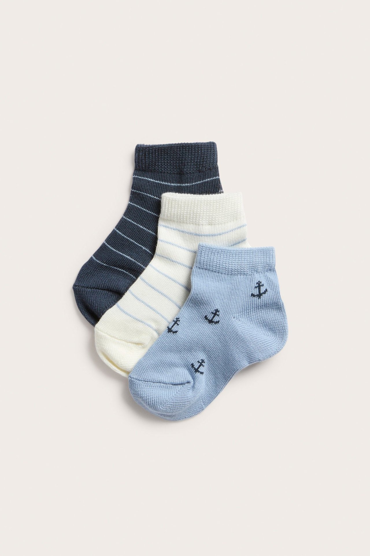 Drei Paar Baby-Sneakersocken: hellblau mit Ankern, cremefarben gestreift und dunkelblau gestreift.