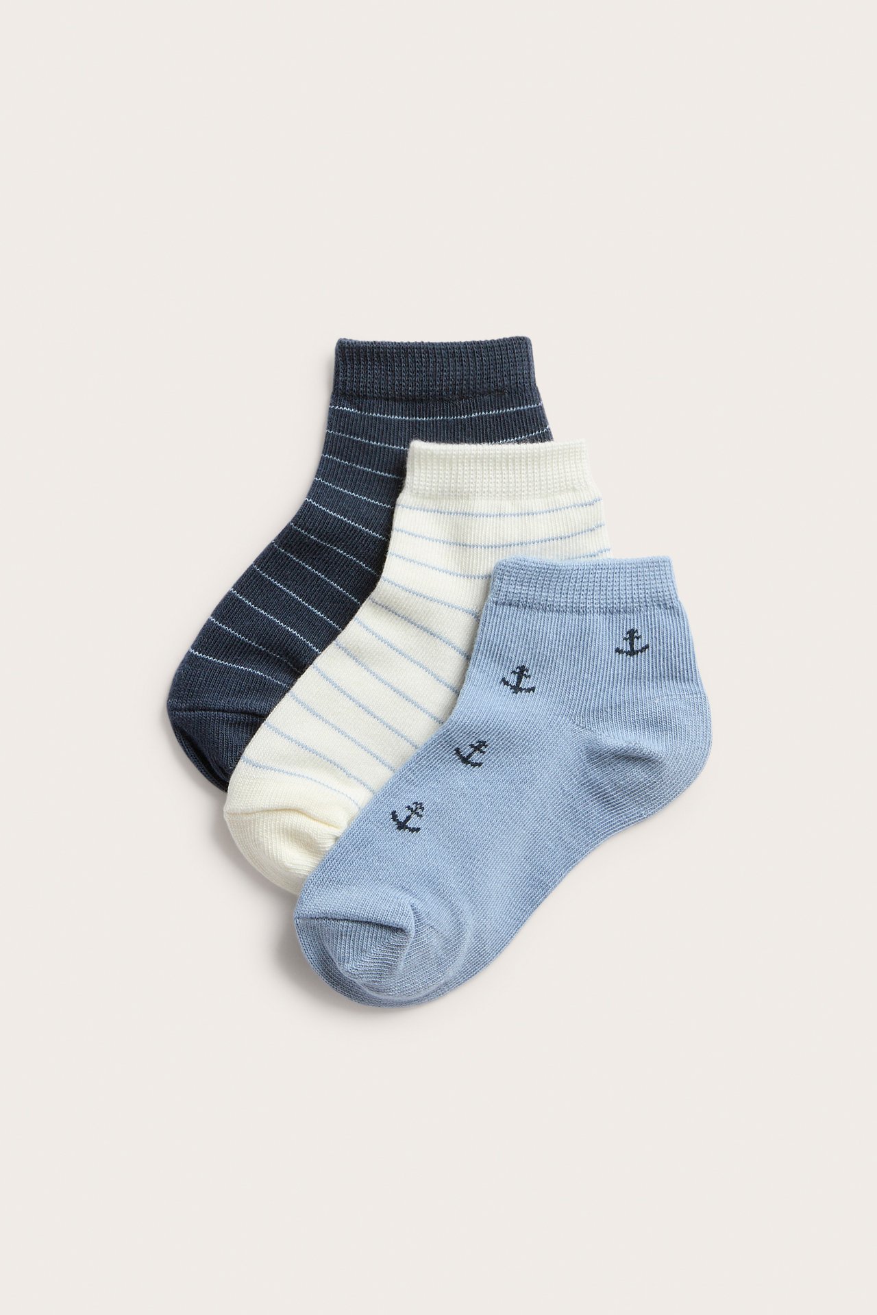Front view of a three-pack of kid's ankle socks: light blue anchors, white stripes, and navy stripes.