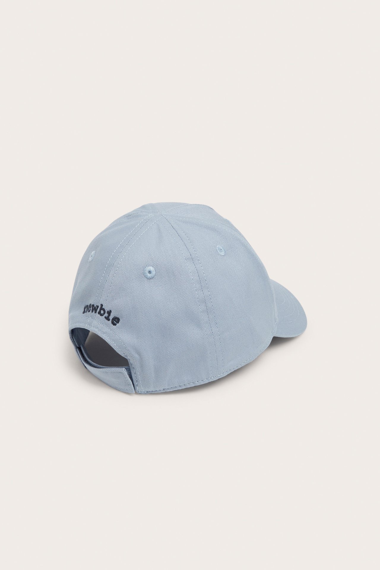 Back-side view of a light blue kid's cotton cap with 'newbie' embroidered in black and an adjustable back strap.