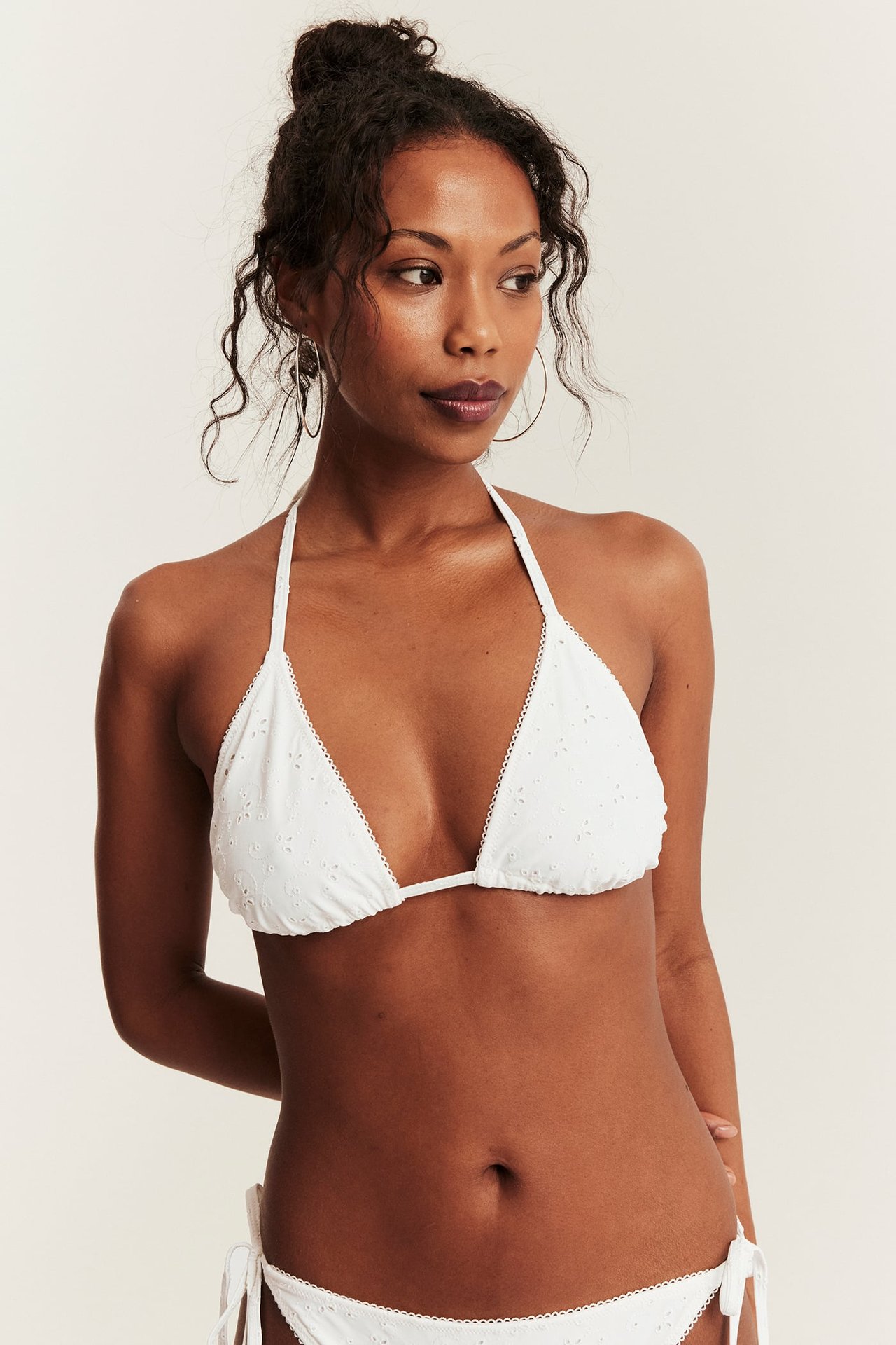 Vorderansicht einer Frau in cremeweißem, besticktem Triangel-Bikini-Top mit Bindebändern und passendem Höschen.