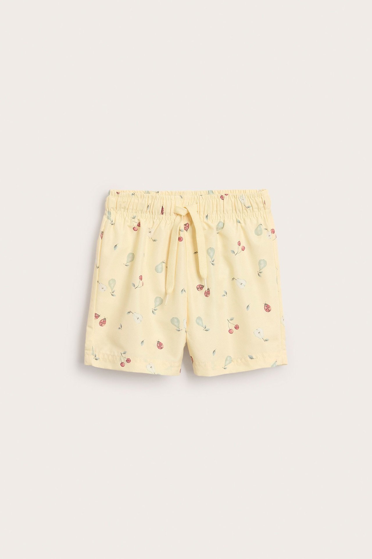 Front view of kid's yellow swim shorts with a fruit pattern, elastic waist, and drawstring.