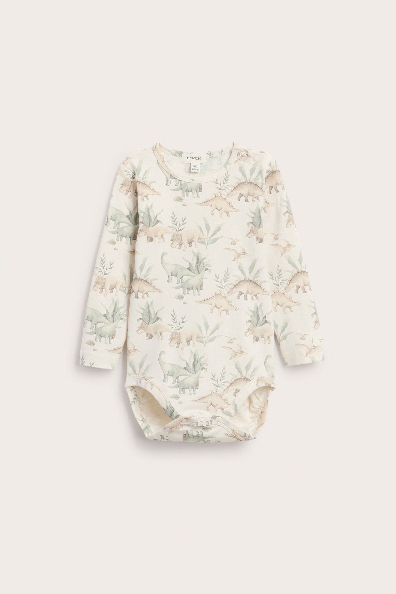 Vorderansicht eines cremefarbenen Langarm-Babybodys mit Dinosaurier- und Blättermuster.