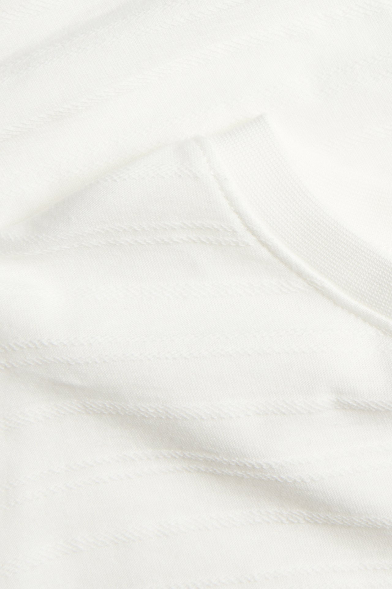 Close-up of a white garment with subtle horizontal textured stripes and ribbed trim.