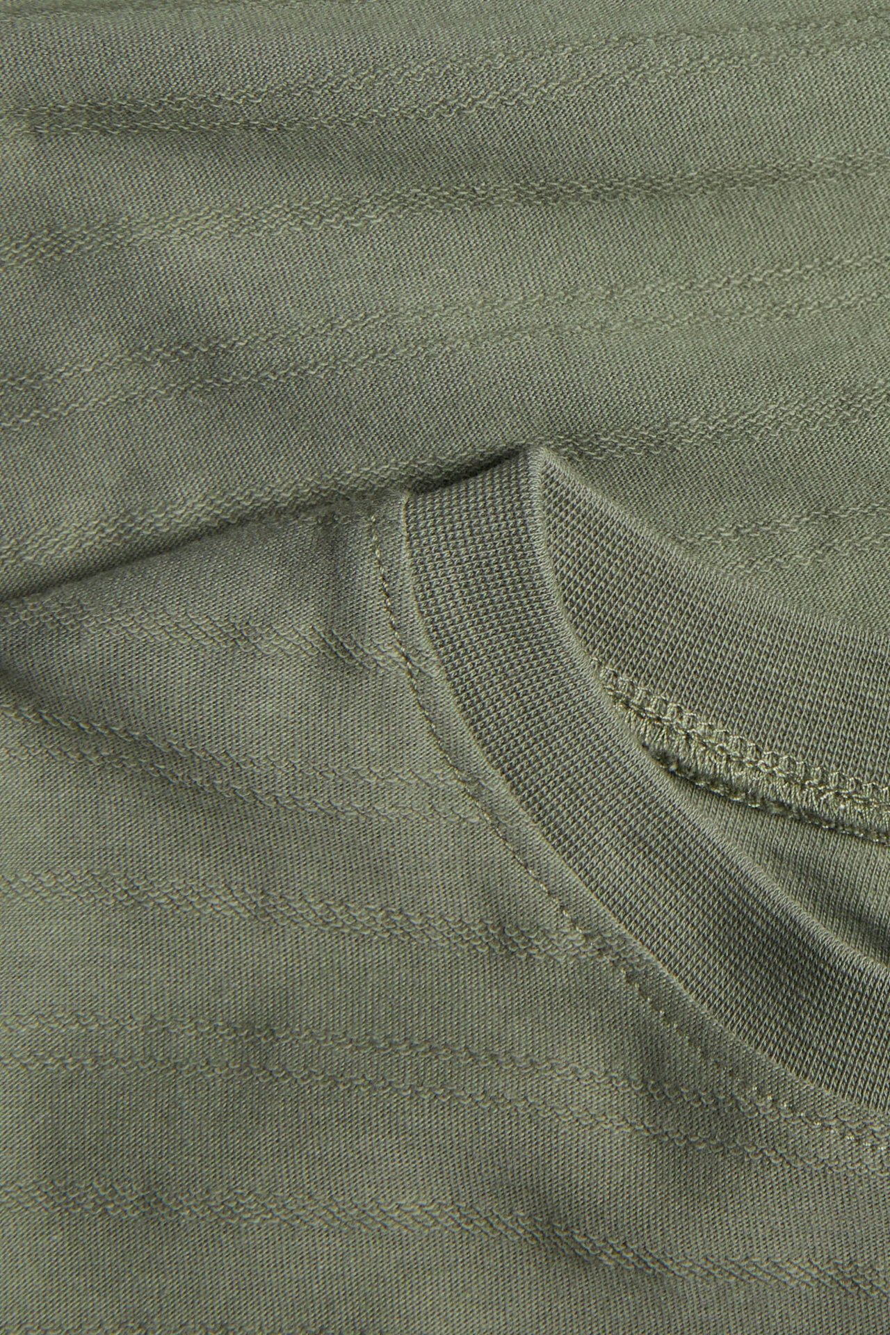 Nahaufnahme eines grünen gerippten Strick-T-Shirts mit sichtbarer Kragennaht.