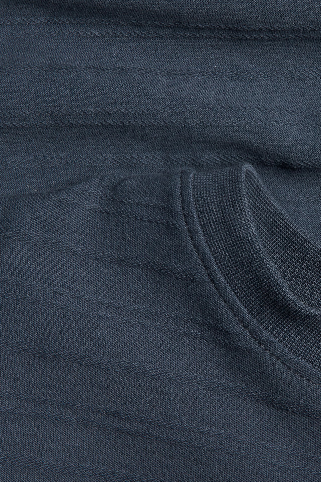 Close-up of a dark blue-gray horizontally textured knit garment with a ribbed collar.