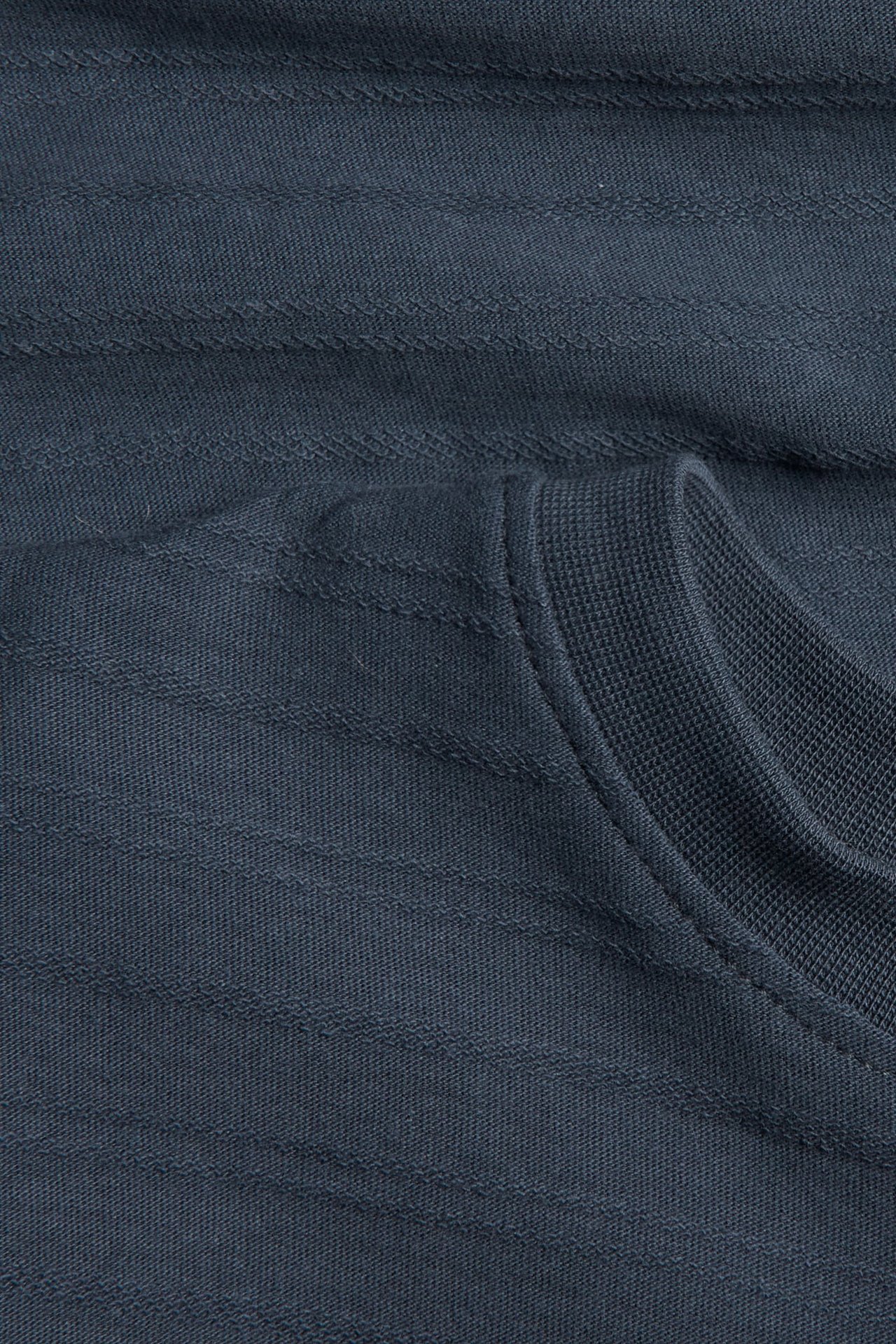 Nahaufnahme eines dunkelblau-grauen, horizontal strukturierten Strickoberteils mit geripptem Kragen.