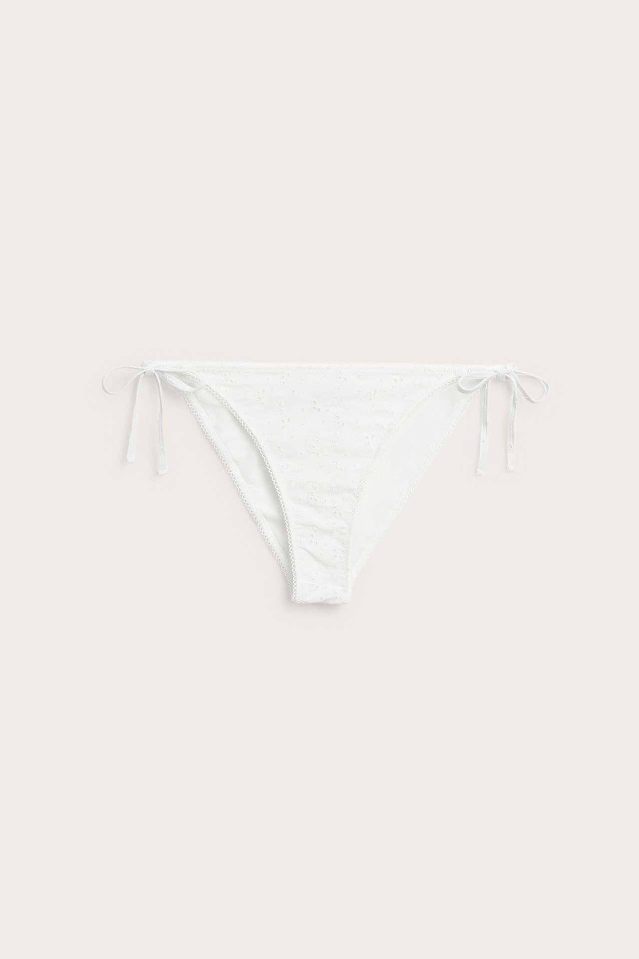 Vorderansicht eines offwhite Damen-Bikinihöschens mit Allover-Stickerei und seitlichen Bindebändern.
