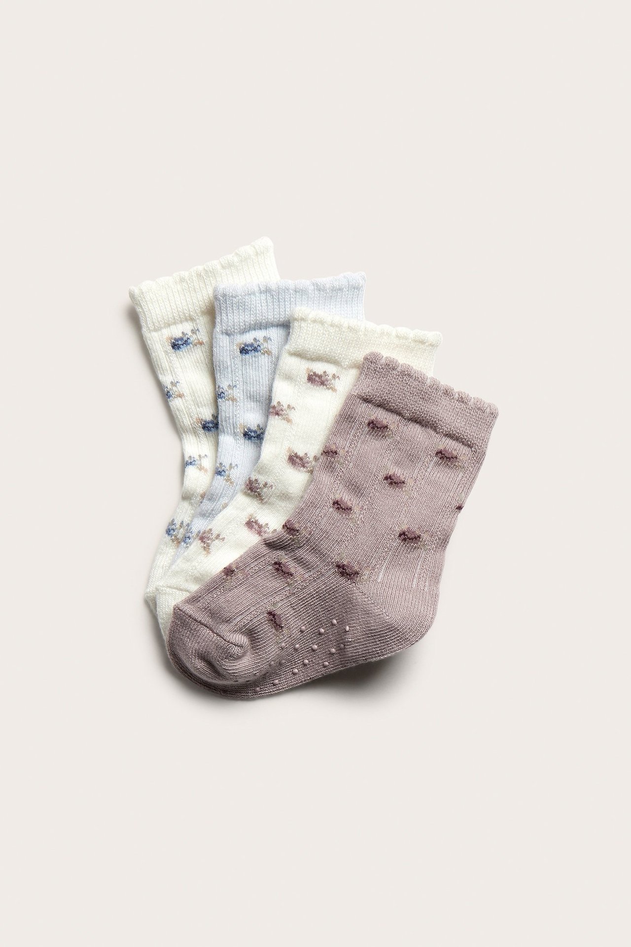Ein 4er-Pack gemusterter Socken in Altrosa, Off-White und Hellblau, mit Blumenmustern und Wellenkanten.