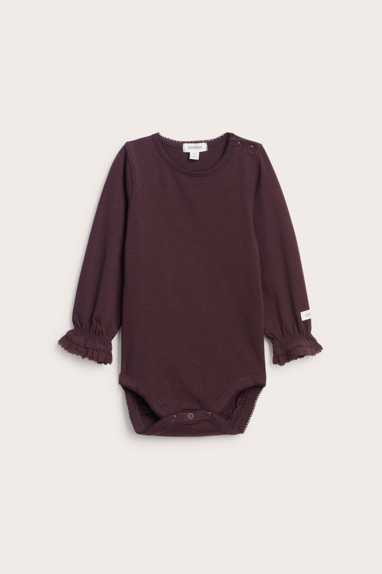 Front view of a baby's dark purple long-sleeved bodysuit with ruffled cuffs.