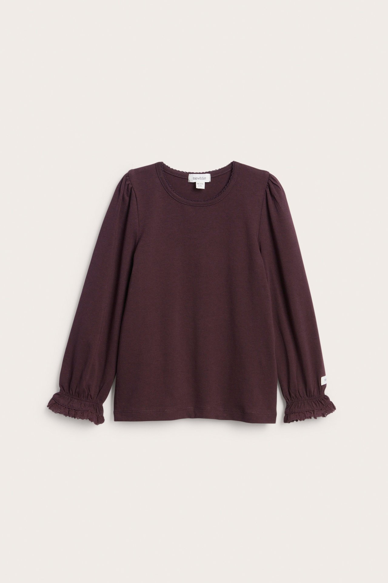 Vorderansicht eines dunkel pflaumenfarbenen Langarmshirts für Kinder mit Rüschenbündchen und Puffärmeln.
