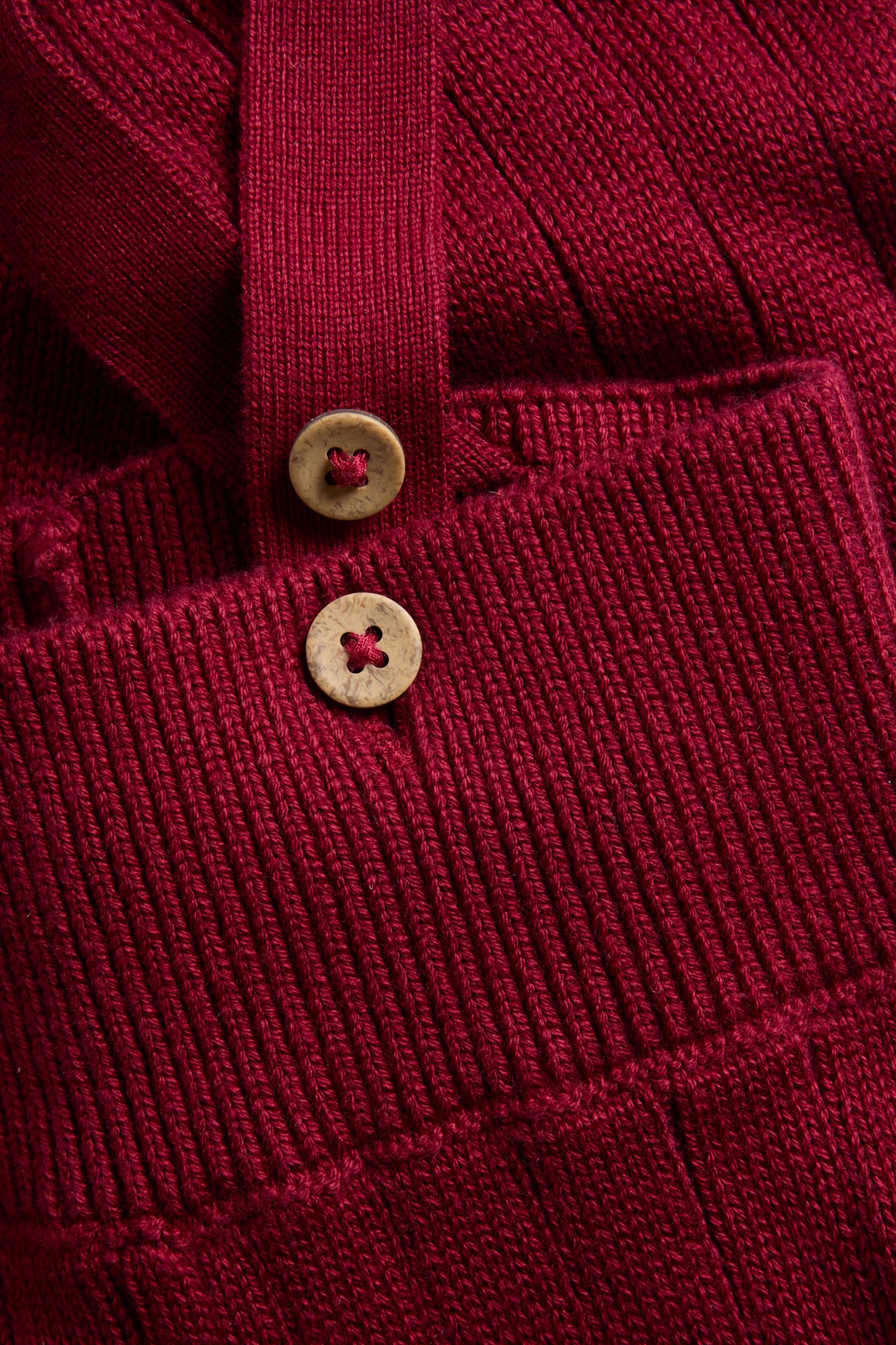 Close-up of a red ribbed knit garment with two wooden buttons.
