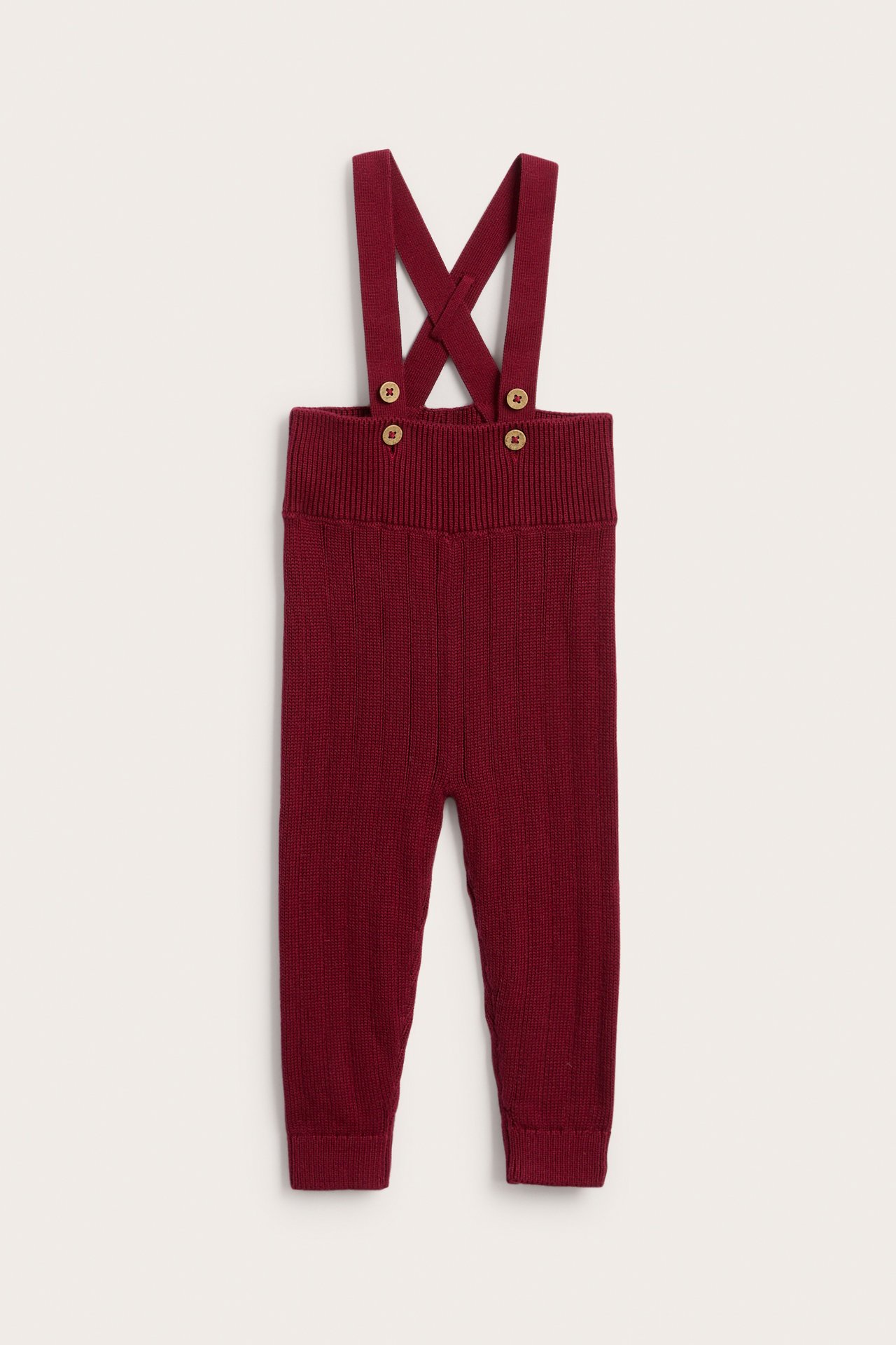 Front view of burgundy knitted kid's overalls with wooden button fastenings.