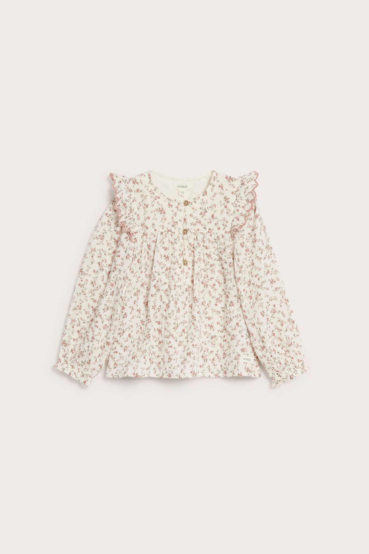Front view of an off-white muslin blouse with a small floral pattern, shoulder ruffles, and front buttons.
