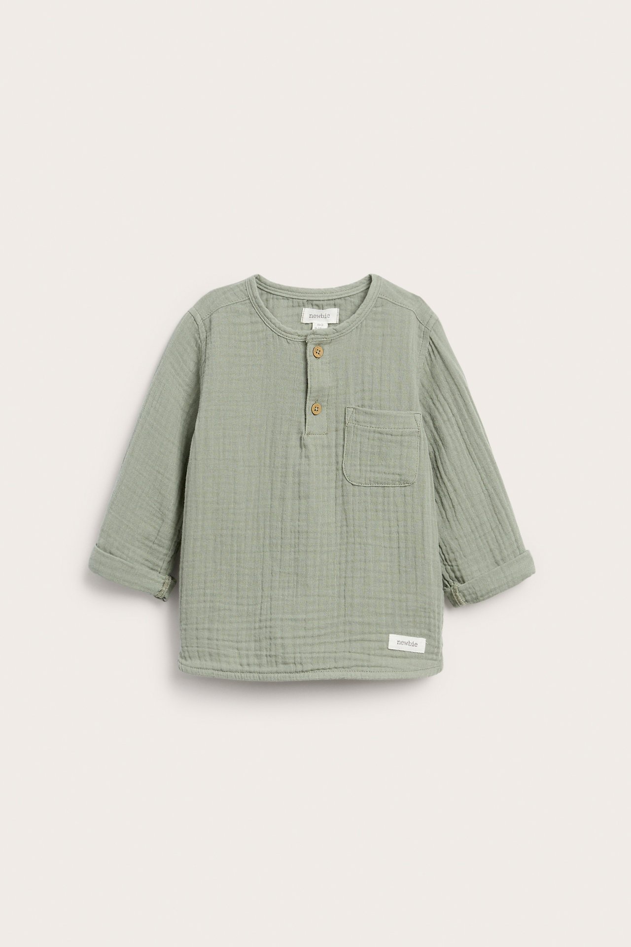 Vorderansicht: Kinder-Langarmshirt aus salbeigrünem Musselin mit Knopfleiste, Brusttasche und umgekrempelten Ärmeln.