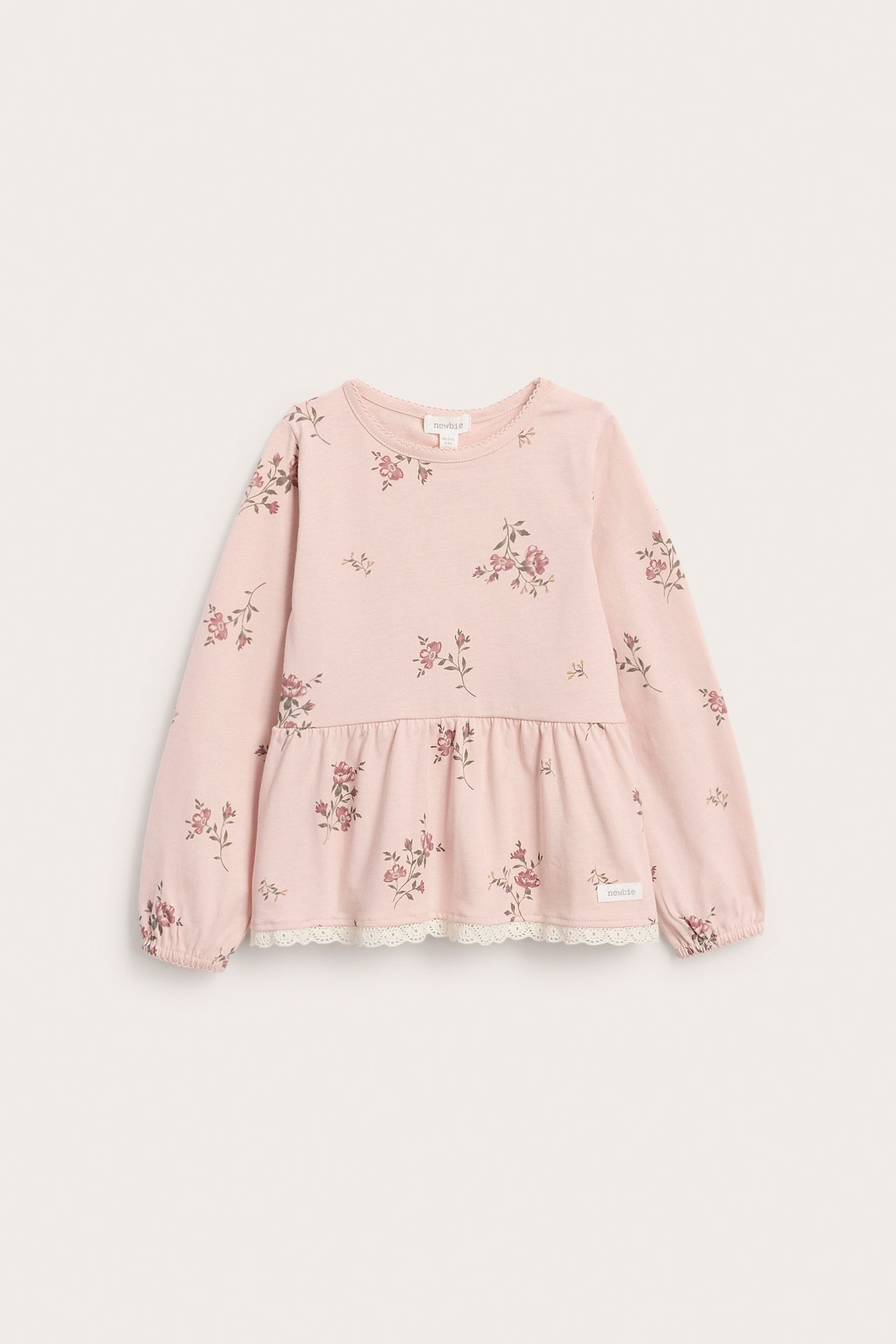 Vorderansicht: hellrosa geblümtes Peplum-Top für Kinder mit langen Ärmeln, elastischen Bündchen, Spitze.
