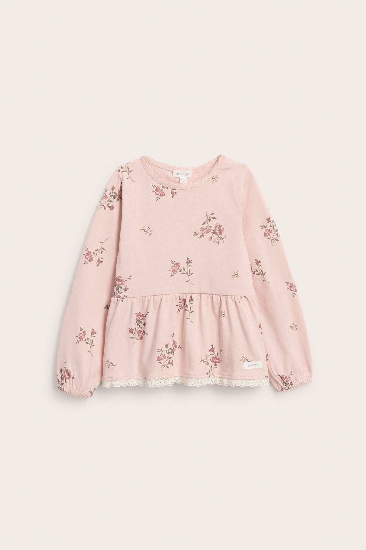 Vorderansicht: hellrosa geblümtes Peplum-Top für Kinder mit langen Ärmeln, elastischen Bündchen, Spitze.