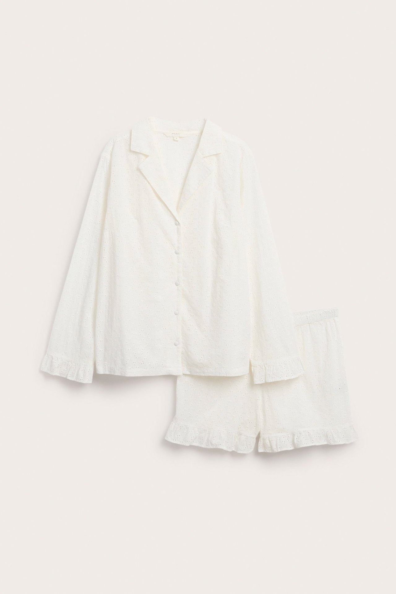 Front view: Off-white cotton broderie anglaise pyjama set, long-sleeved shirt and shorts with ruffle details.