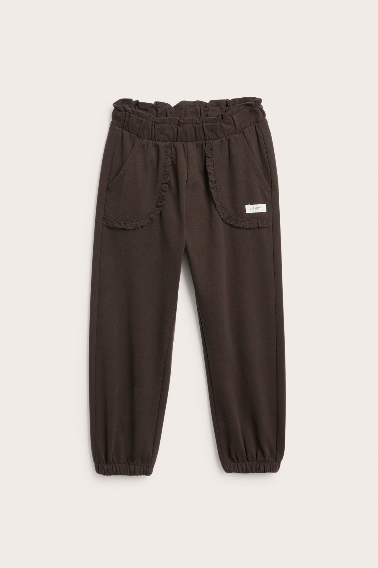 Vorderansicht von dunkelbraunen Kinder-Jogginghosen mit Rüschenbund und Taschen, elastische Bündchen.