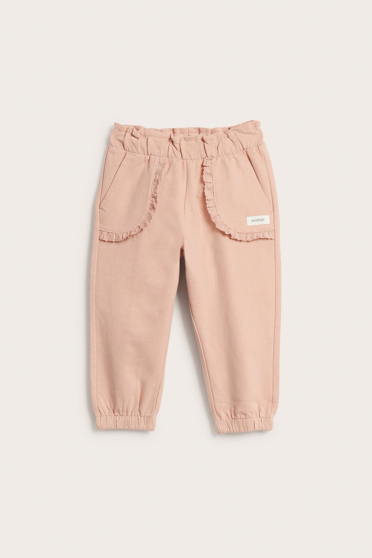Vorderansicht: Kinder-Jogginghose aus rosa Baumwolle mit Spitzentaschen, verstellbarem Gummibund und elastischen Beinbündchen.