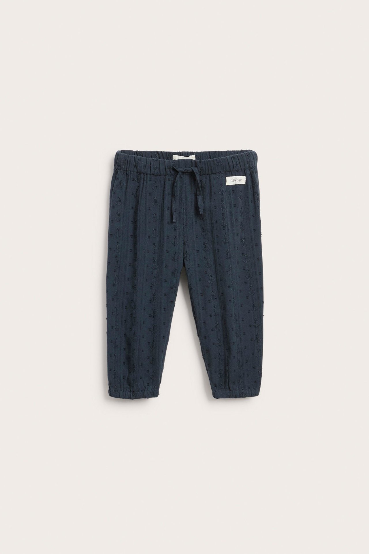 Front view: dark blue baby's woven cotton trousers with elastic drawstring waist and subtle texture.