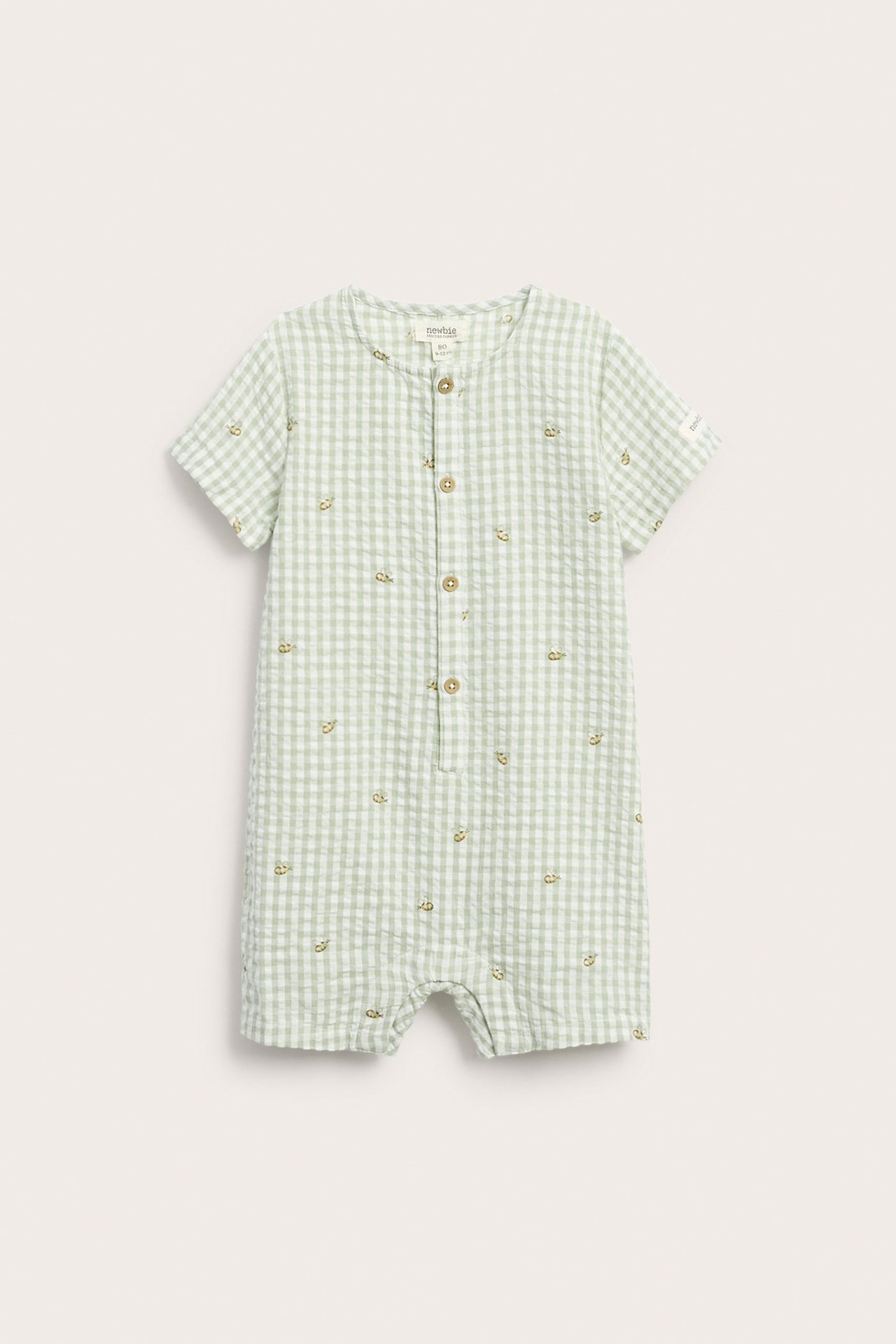 Front view: Green checked baby romper with short sleeves, front buttons, snap fasteners, and bee pattern.