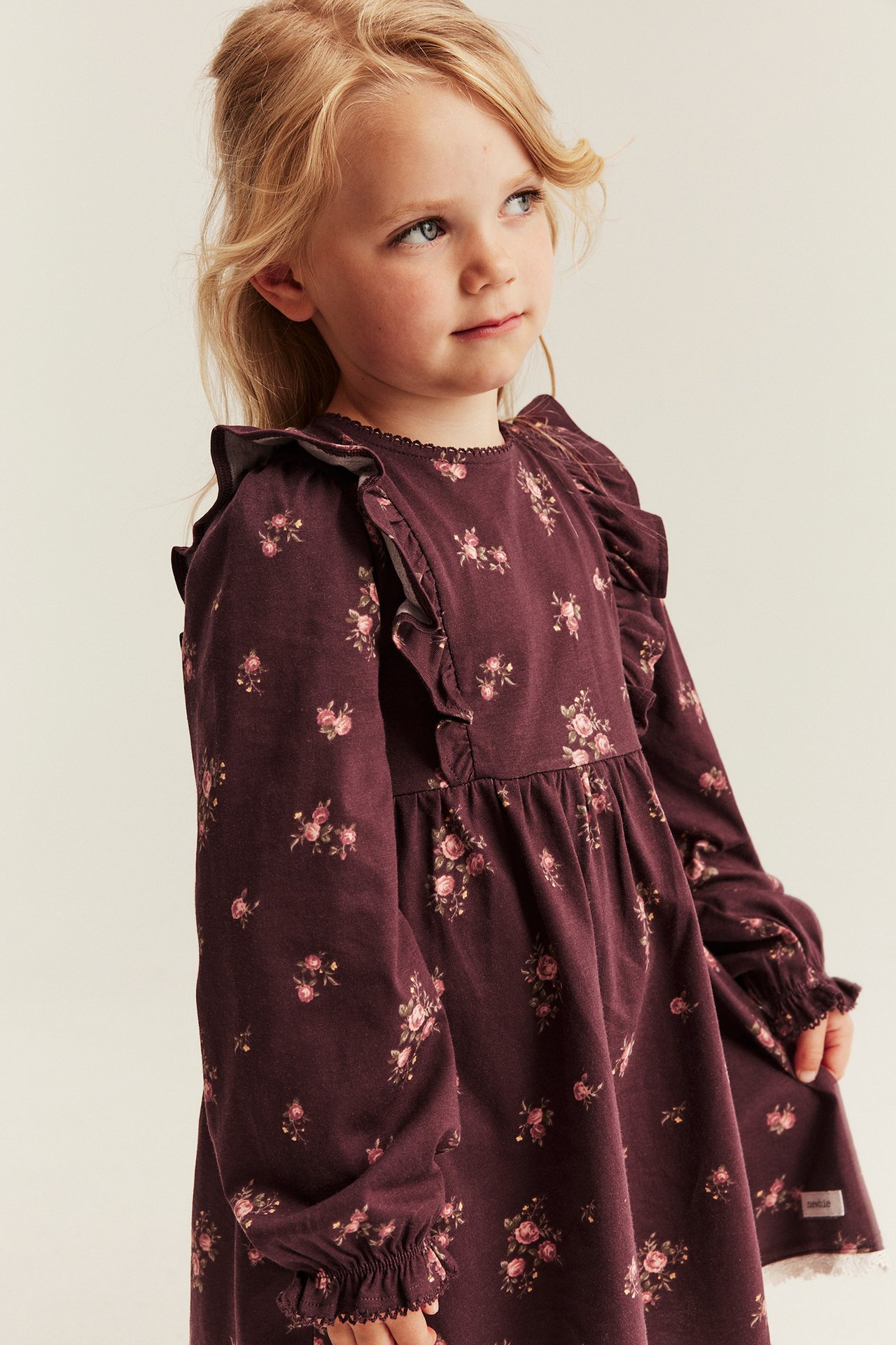 Kid's plum floral long-sleeved dress with ruffles, front-side view.