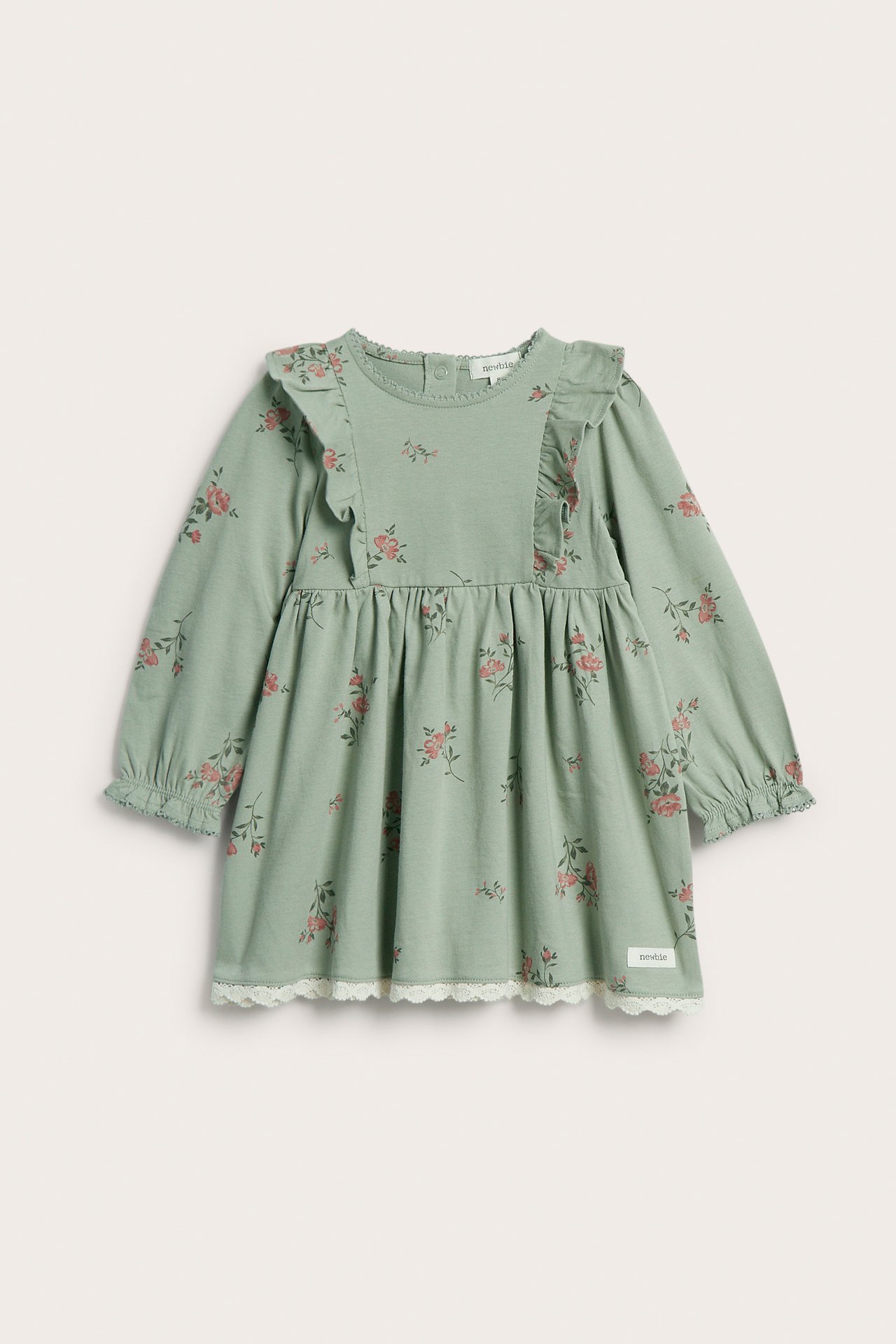 Front view of a green cotton baby dress with pink floral print, shoulder ruffles, and white lace hem.