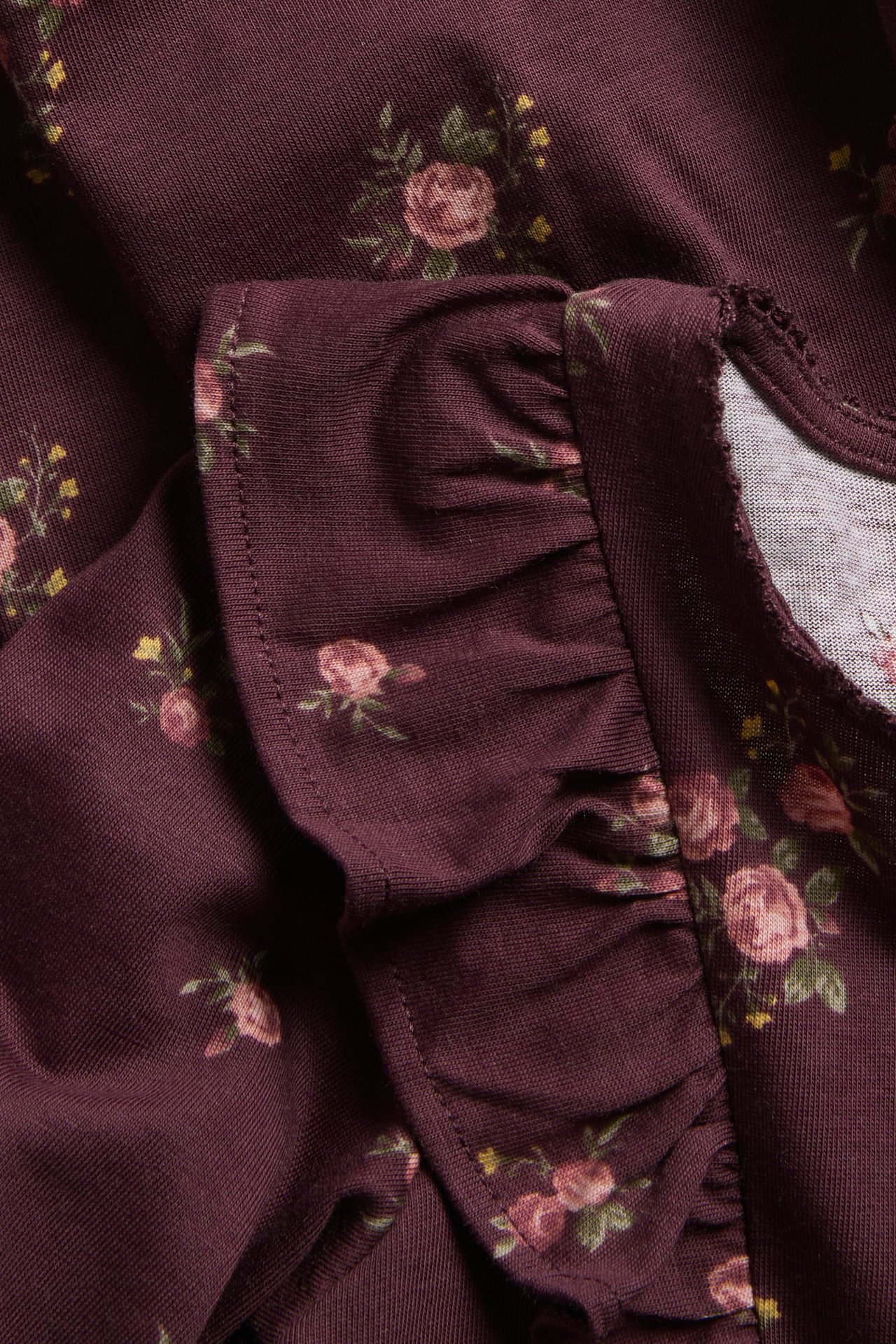 Close-up of a wine red floral cotton jersey dress with shoulder ruffles.