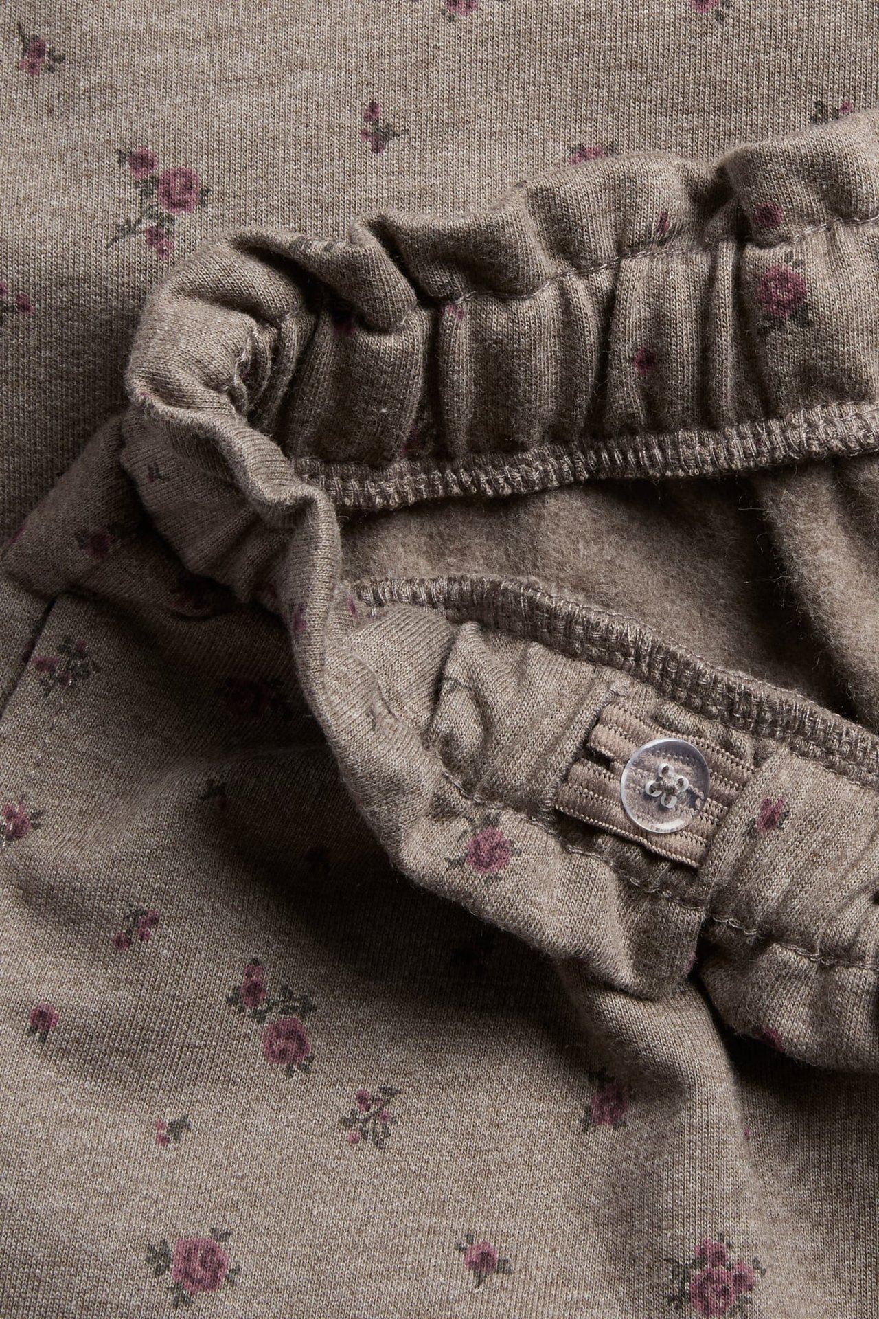 Nahaufnahme von braunen Kinderhosen mit Blumenmuster und verstellbarem Gummibund.