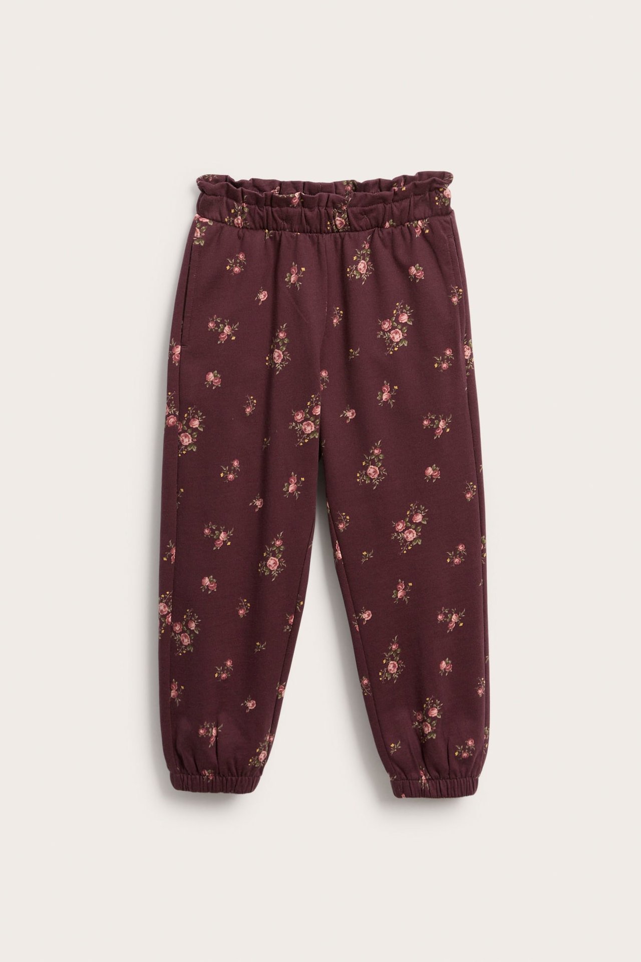 Front view of kid's burgundy floral sweatpants with ruffled elasticated waist and cuffs.