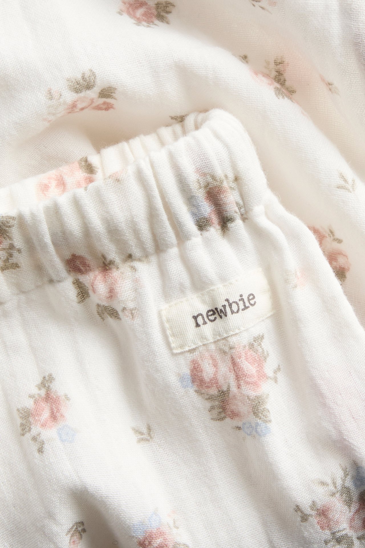 Nahaufnahme von cremeweißen dünnen Baumwollhosen mit zartem Blumenmuster und elastischem Bund.