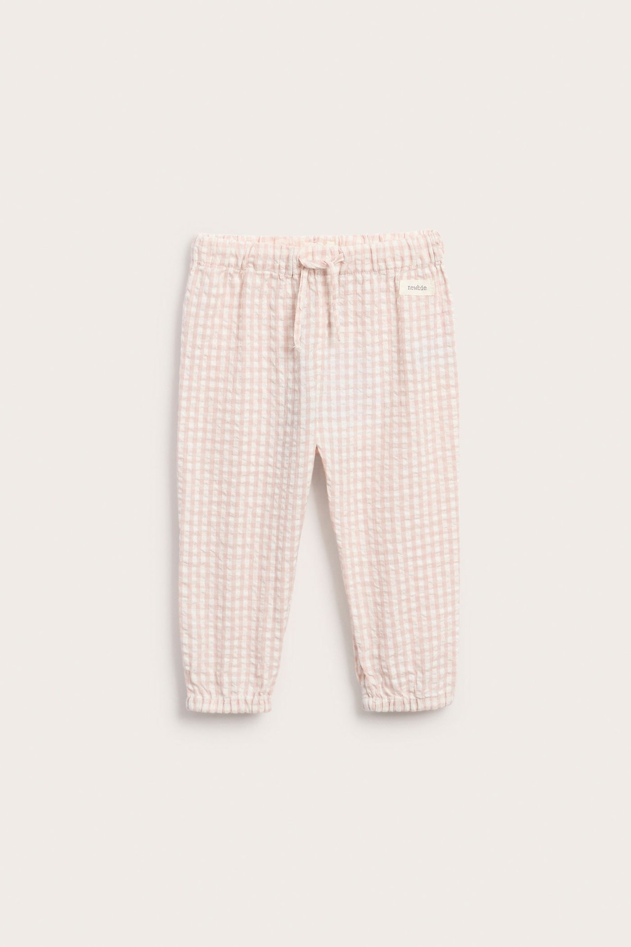 Front view of baby's light pink and white checked woven cotton trousers with an elastic drawstring waist and cuffs.