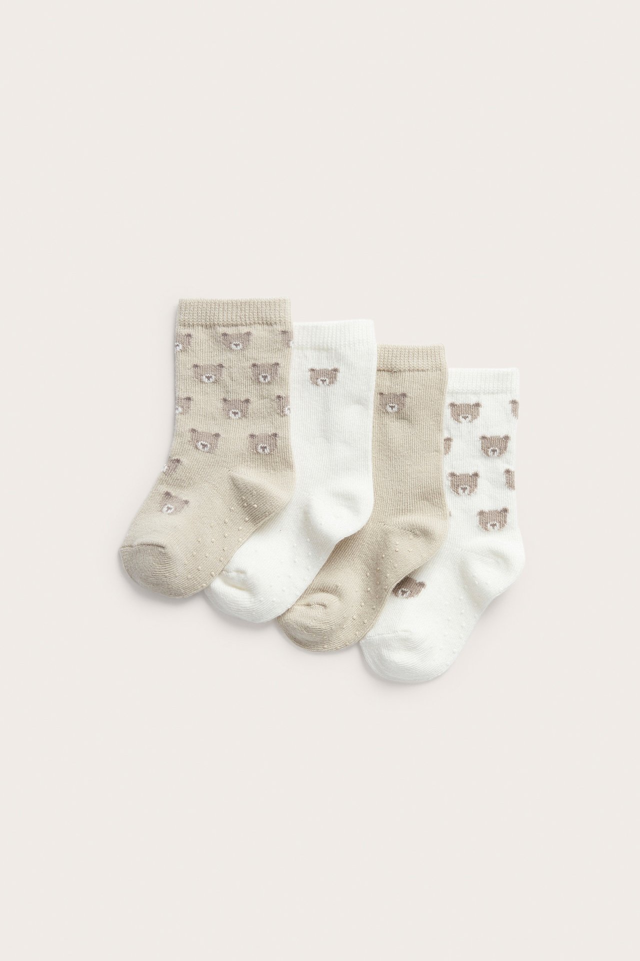 Vier Paar Babysocken in Beige und Off-White mit Bärchengesichtern und Antirutsch-Noppen. Draufsicht.