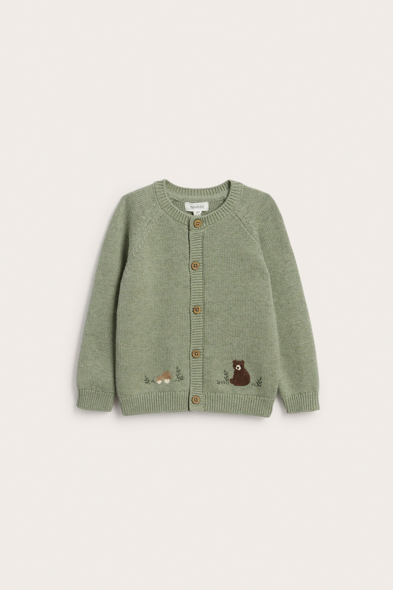 Vorderansicht: Hellgrüner gestrickter Baby-Cardigan mit gesticktem Bär, Pilzen und Holzknöpfen.