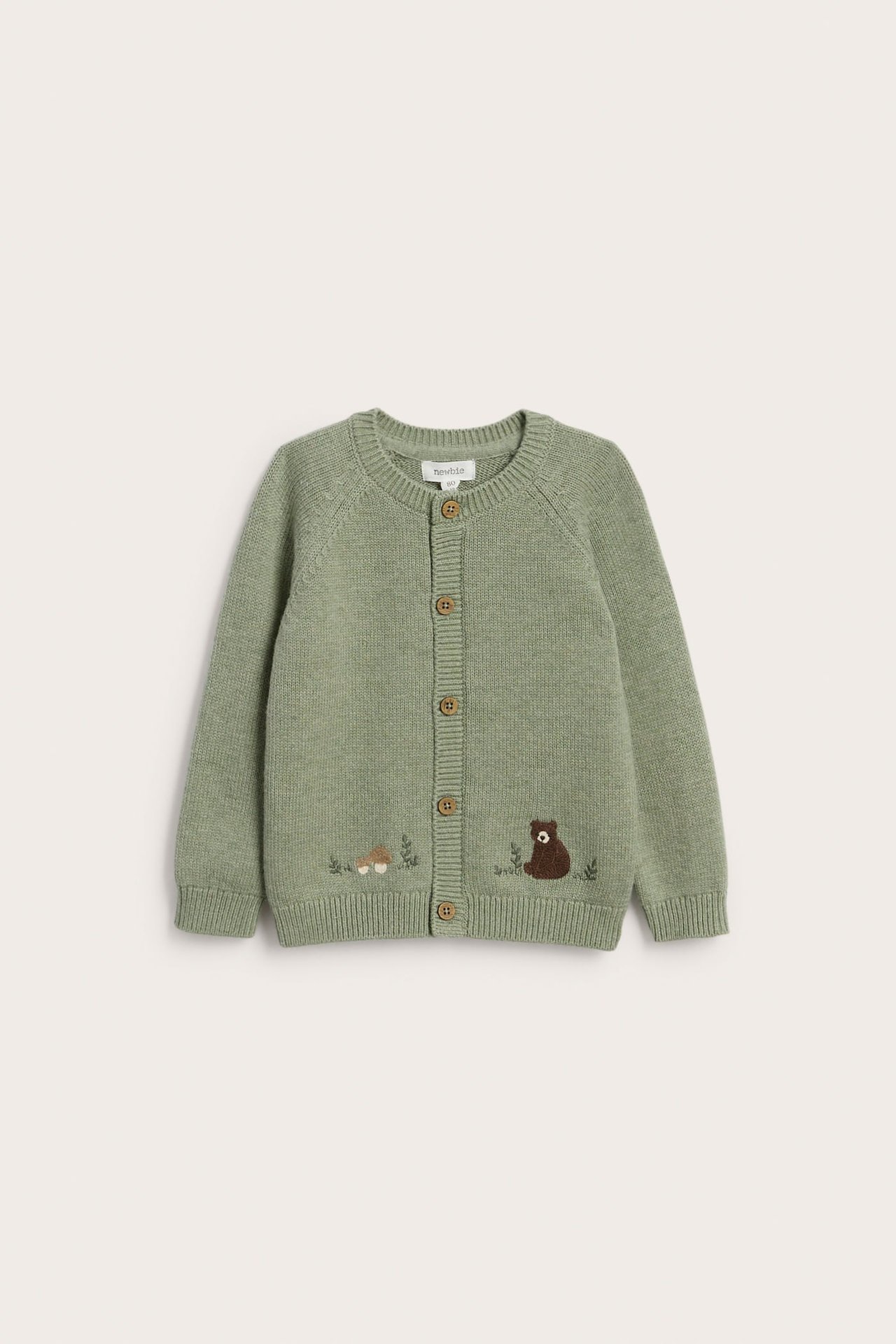 Vorderansicht: Hellgrüner gestrickter Baby-Cardigan mit gesticktem Bär, Pilzen und Holzknöpfen.