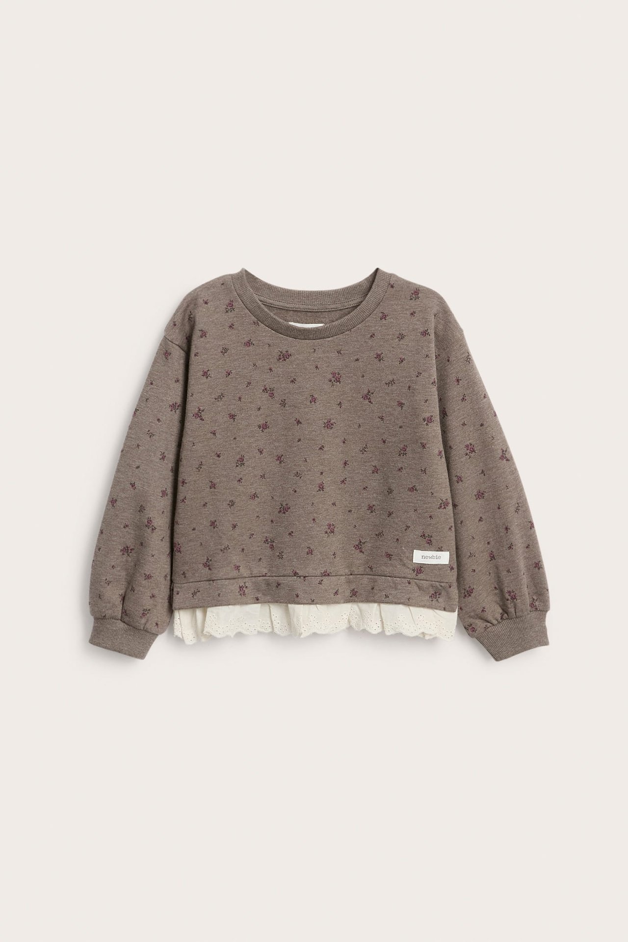 Vorderansicht eines braunen gemusterten Kindersweatshirts mit weißem Spitzenvolant.
