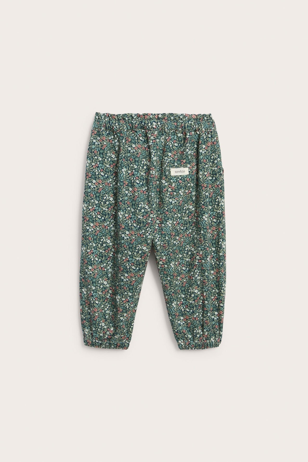 Front view of kid's dark green floral print pants with elasticated waist and cuffs.