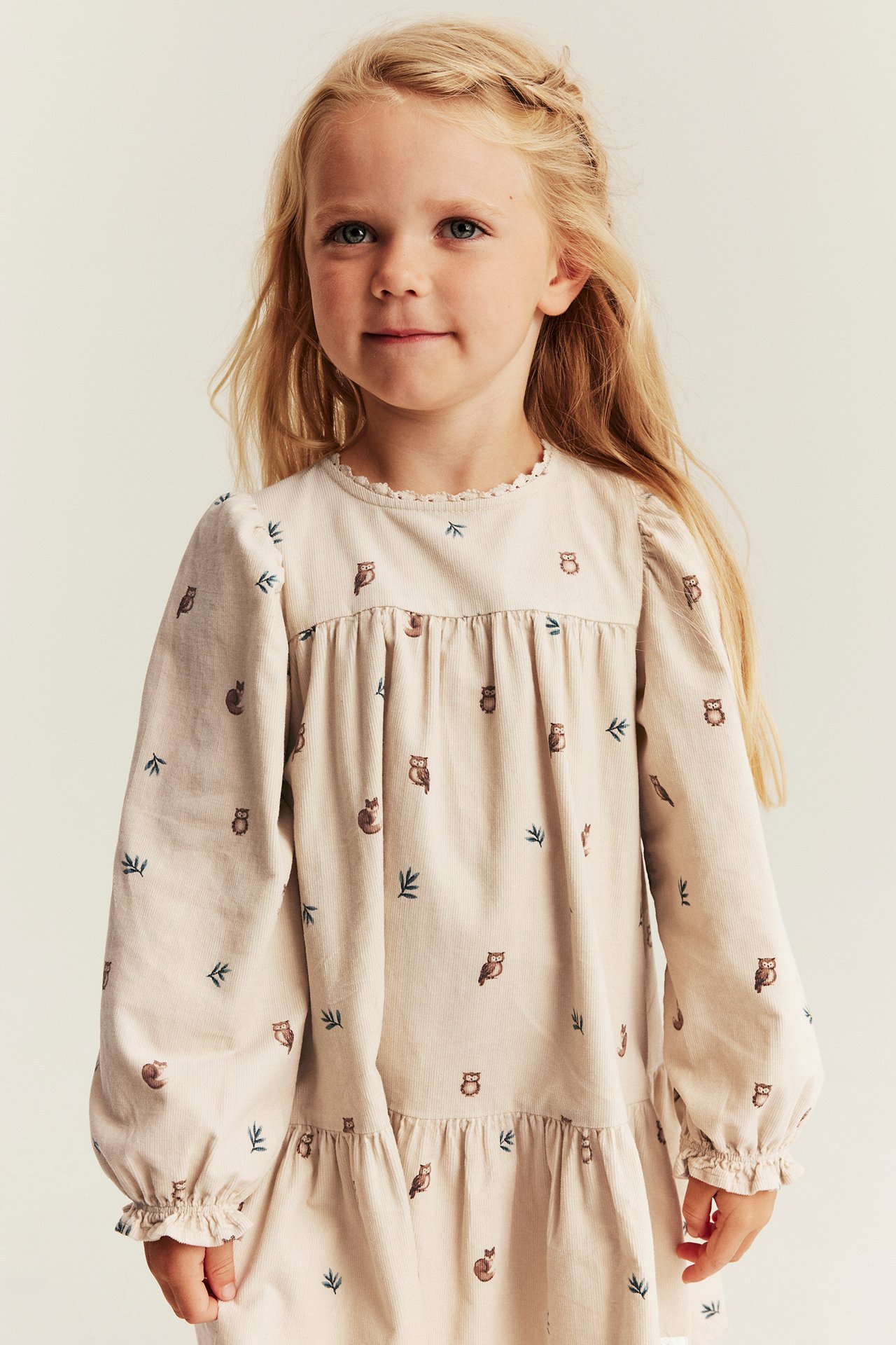 Vorderansicht: Kinder hellbeiges Cordkleid mit Eulen- und Blättermuster.