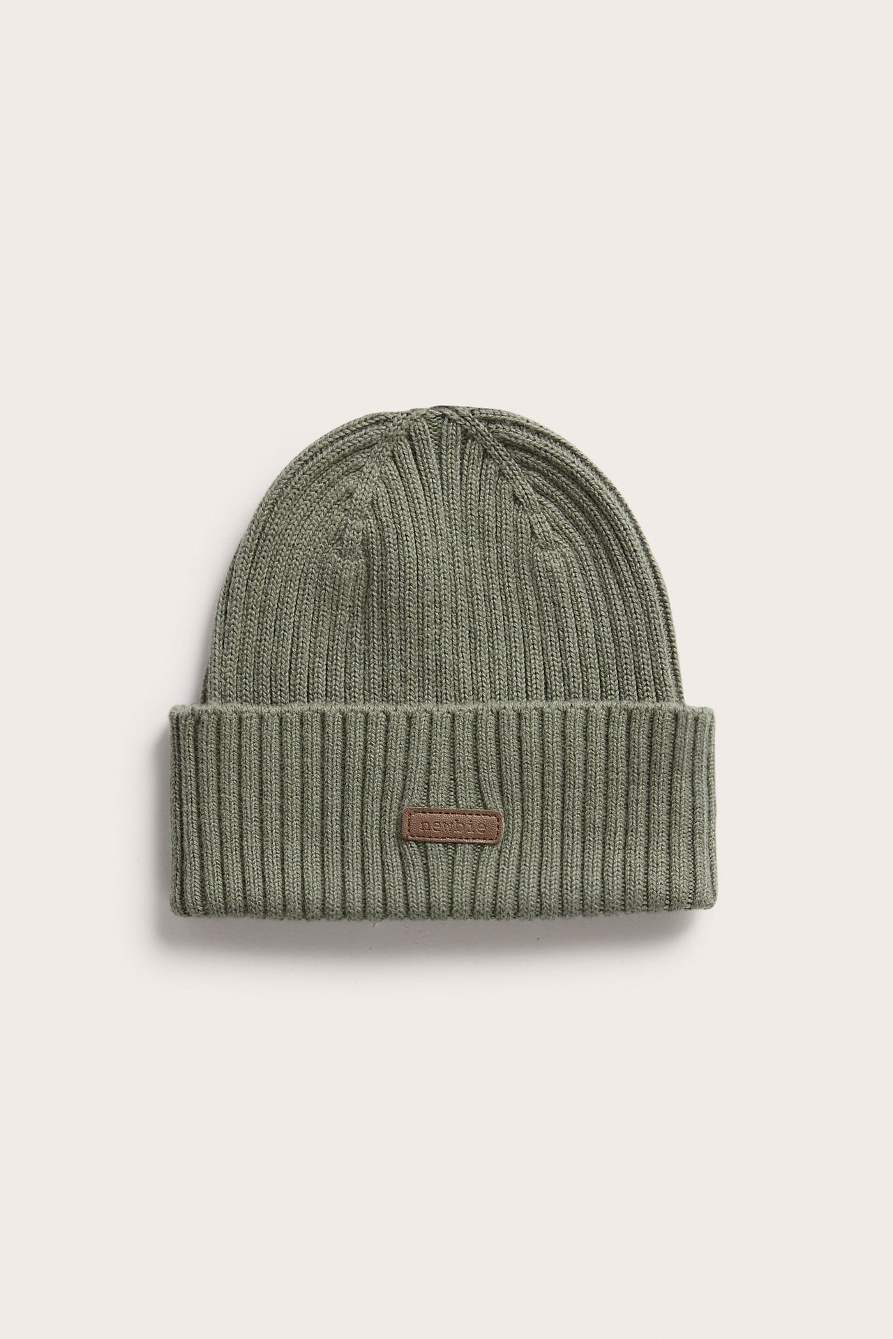 Vorderansicht einer grünen gerippten Strickmütze mit braunem 'newbie'-Etikett.