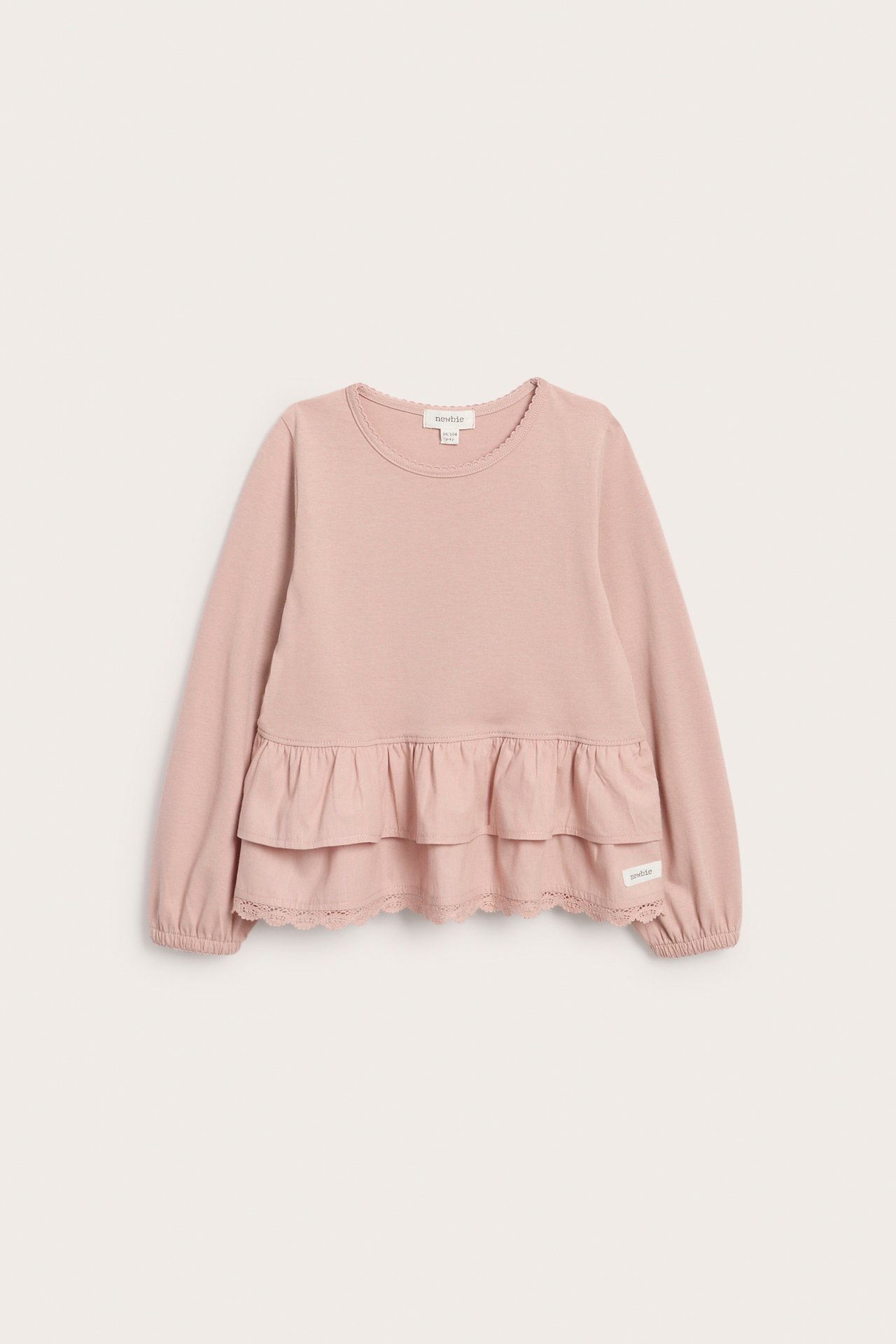 Vorderansicht eines rosa langärmeligen Kinder-Oberteils mit Rüschen und Wellenkante.