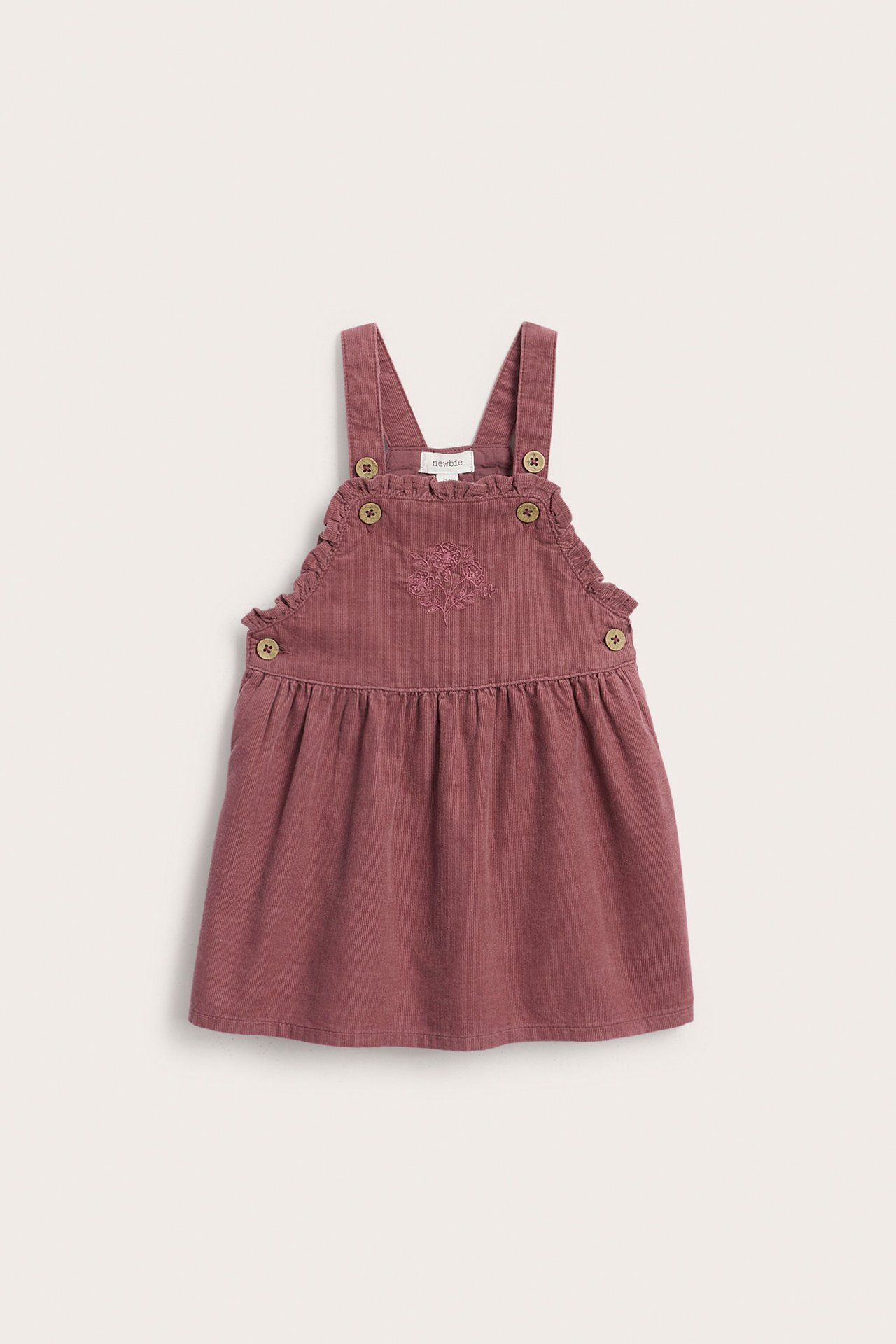 Vorderansicht eines baby Latzkleids aus Cord mit Blumenstickerei und Knöpfen in Altrosa.