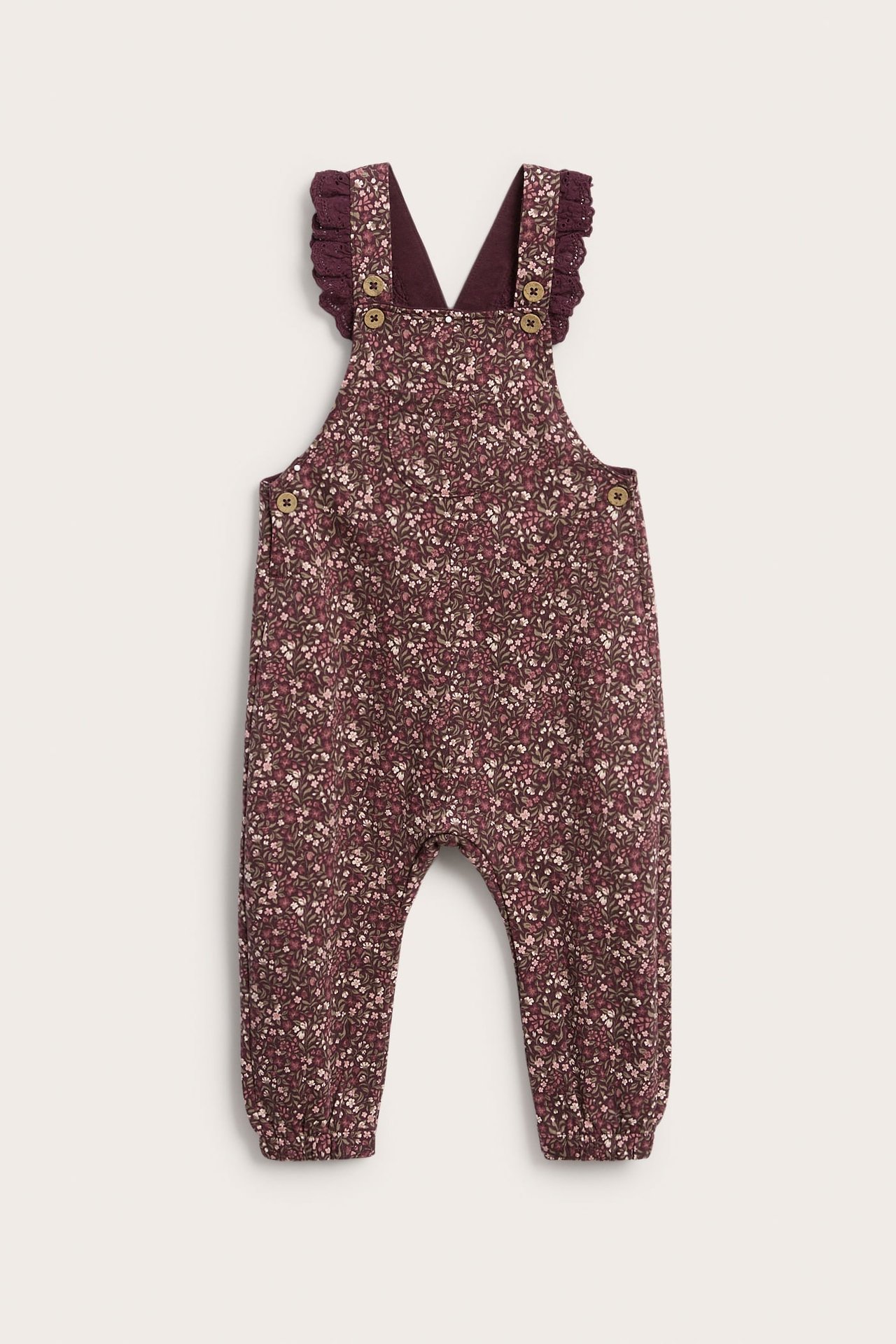Vorderansicht Babys Blumen-Overall mit Rüschenträgern und dunklem Oberteil darunter.
