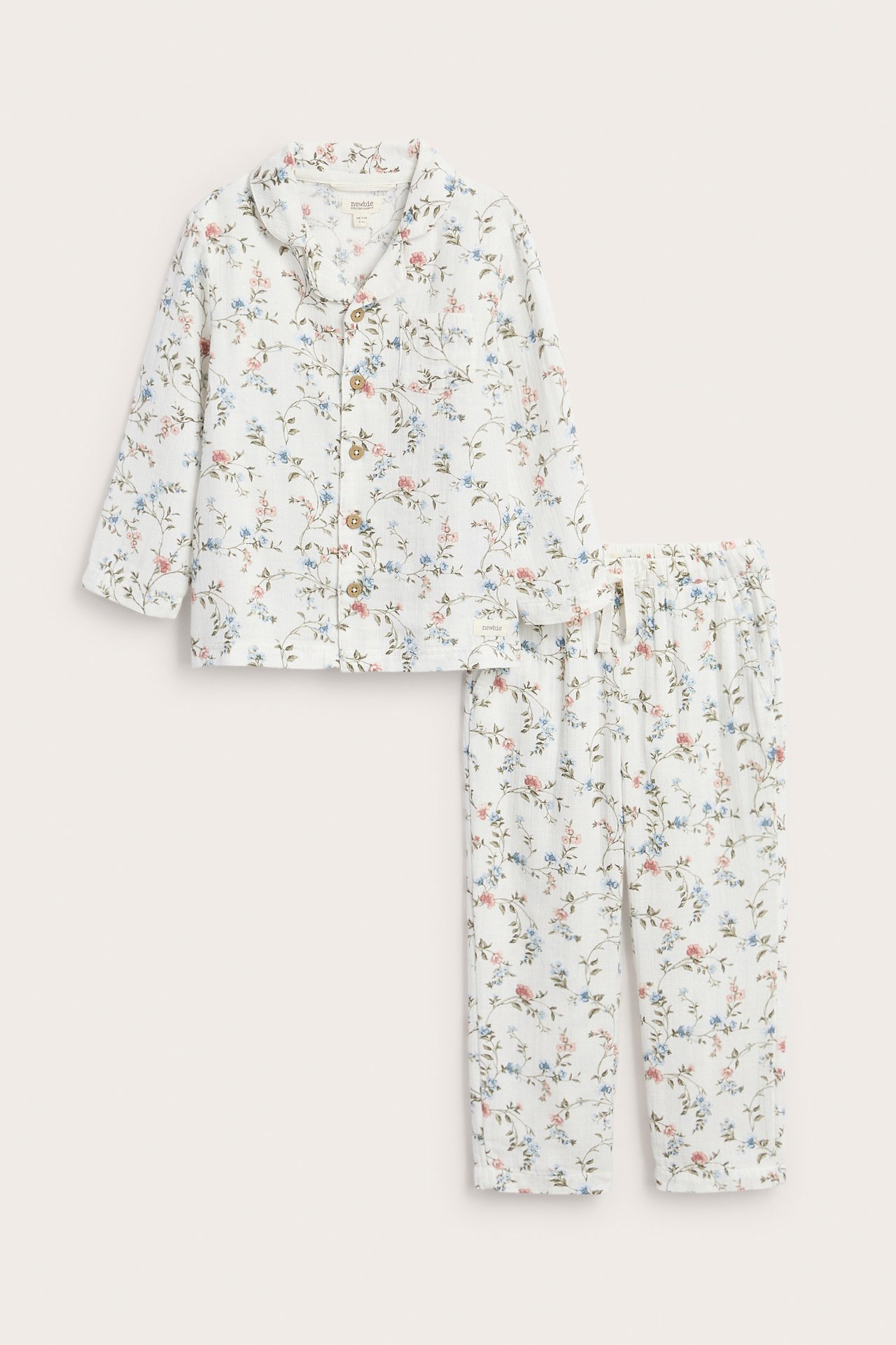 Front view of an offwhite kid's two-piece cotton pajama set with a blue and pink floral pattern.