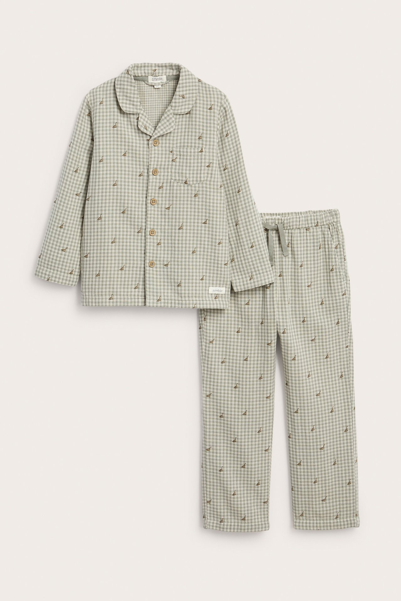 Front view of a light green cotton pajama set: collared shirt and pants with dinosaur check print.